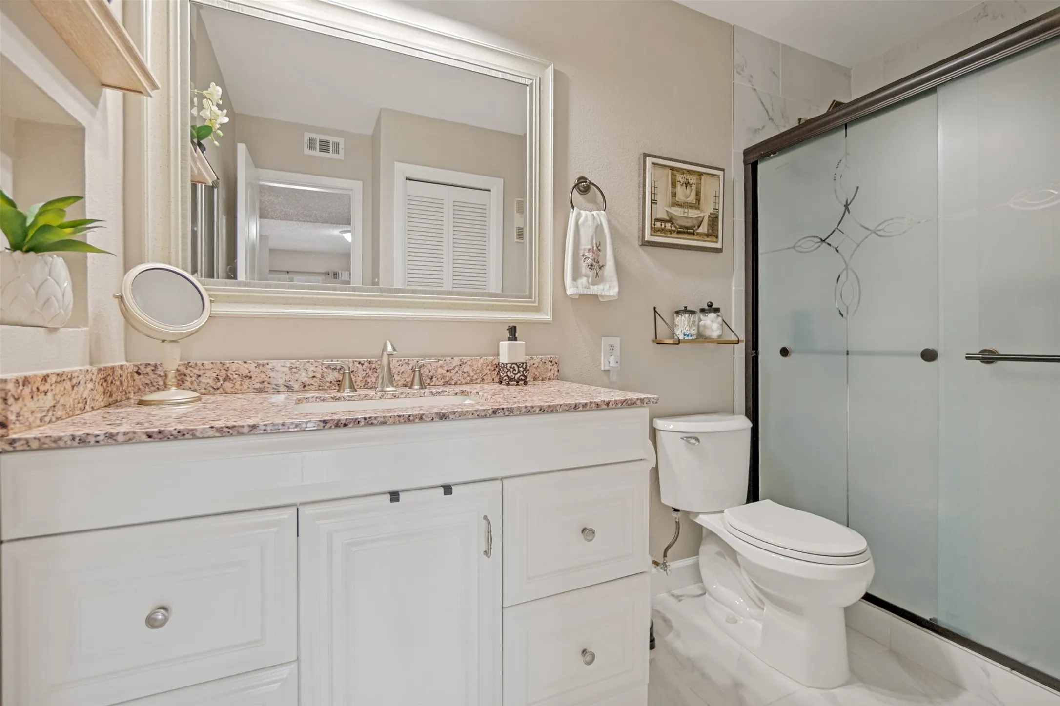 White shaker vanity with a light-toned countertop, undermount sink, and polished chrome faucet