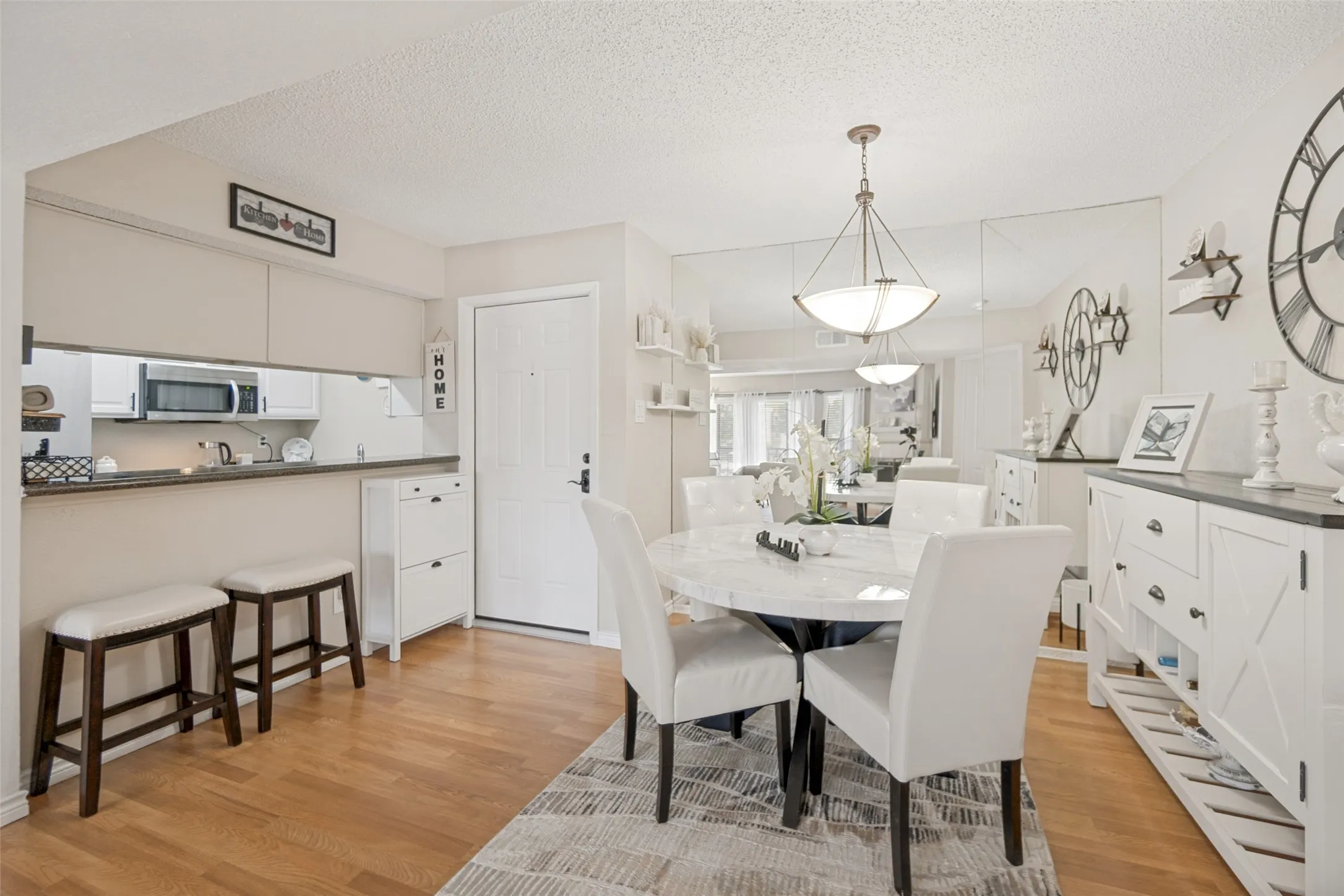 Open concept dining area featuring wood-finish flooring, a contemporary pendant light fixture, and a built-in kitchen pass-through with counter seating