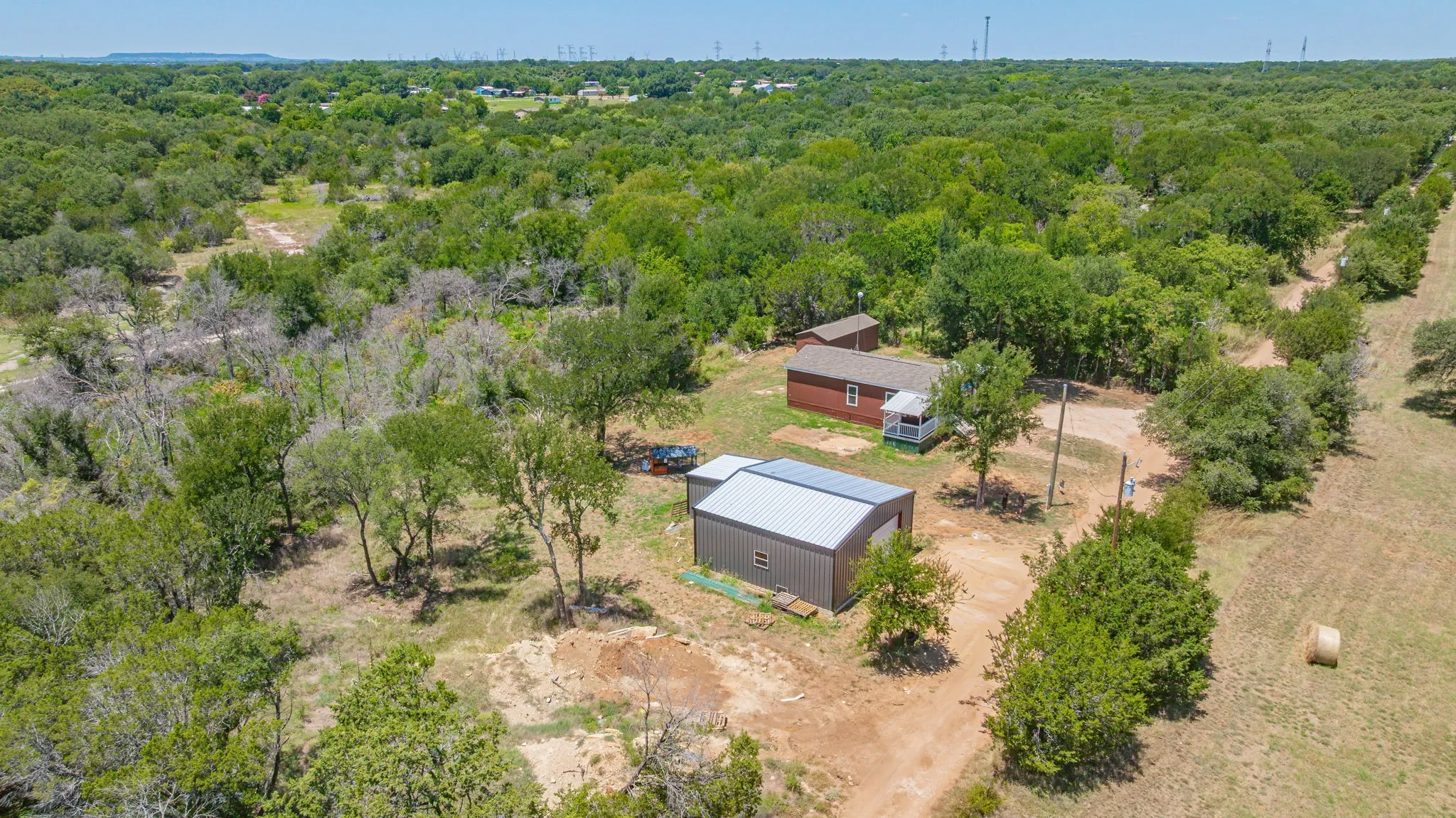 Aerial perspective showcasing a single-story dwelling with a red siding exterior and a white porch