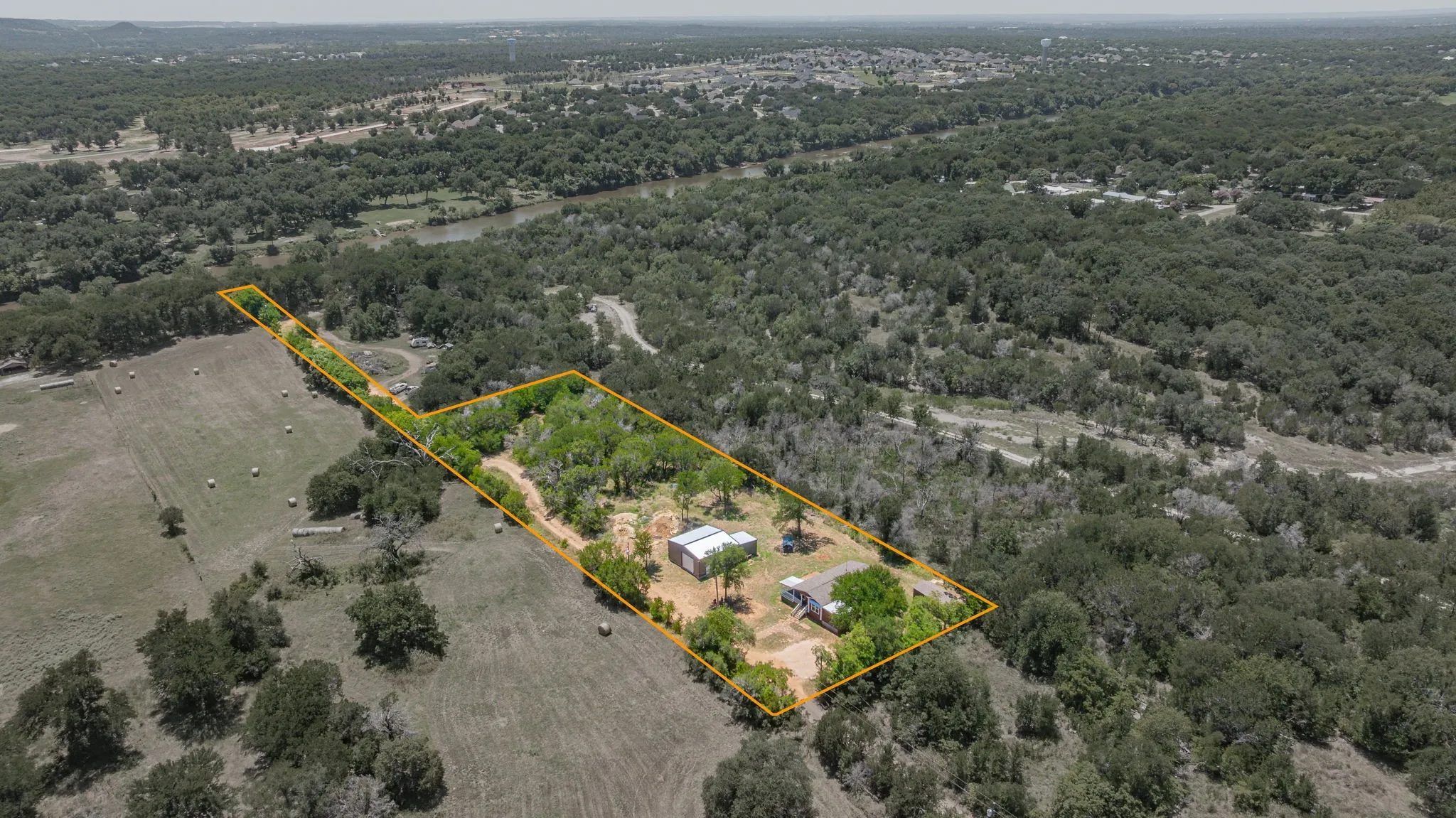 Expansive natural landscape featuring a river, mature tree cover, and a cleared building site