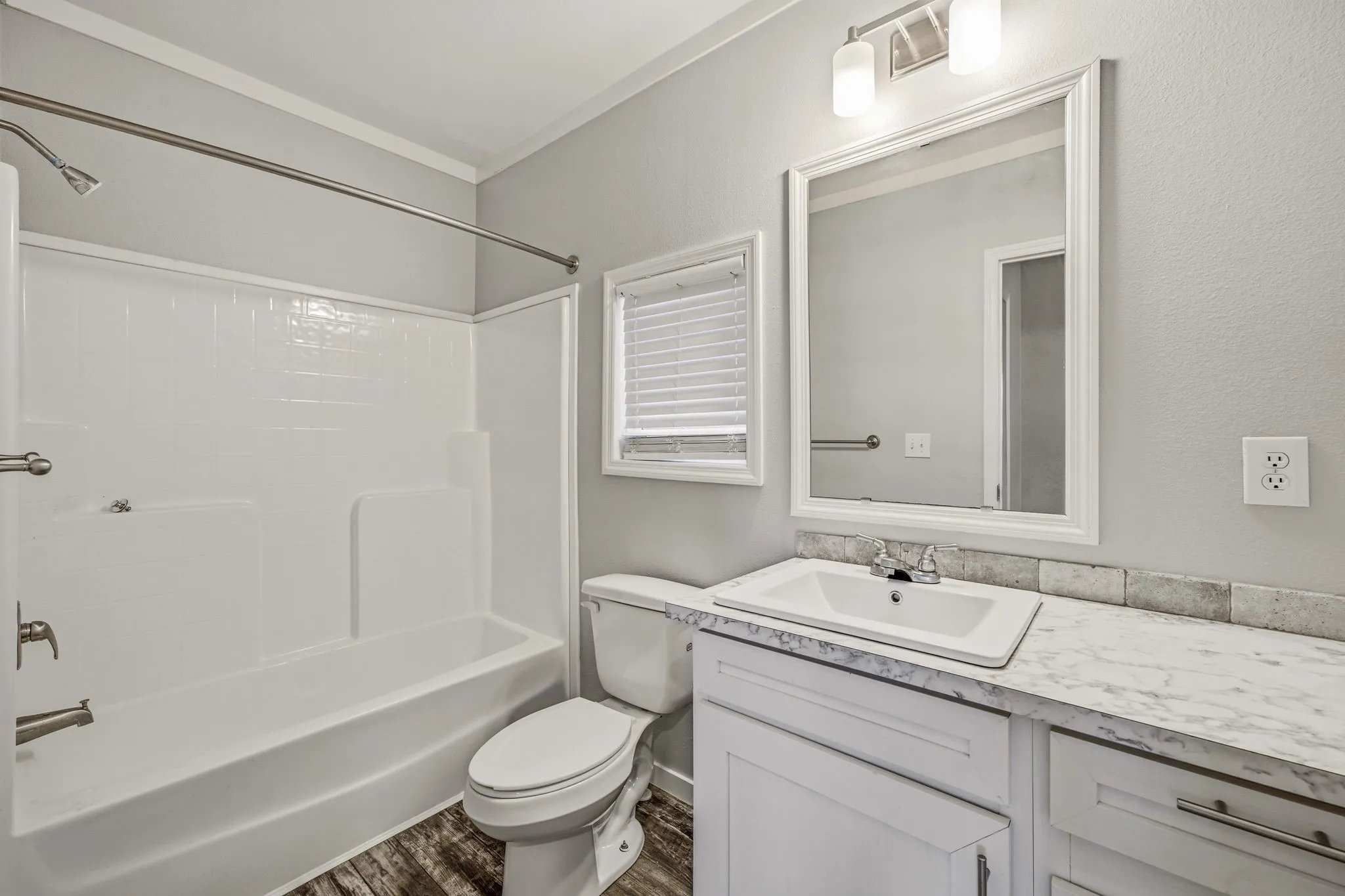 Bathroom featuring a white vanity with an integrated sink, a marble-patterned countertop, and a tiled backsplash