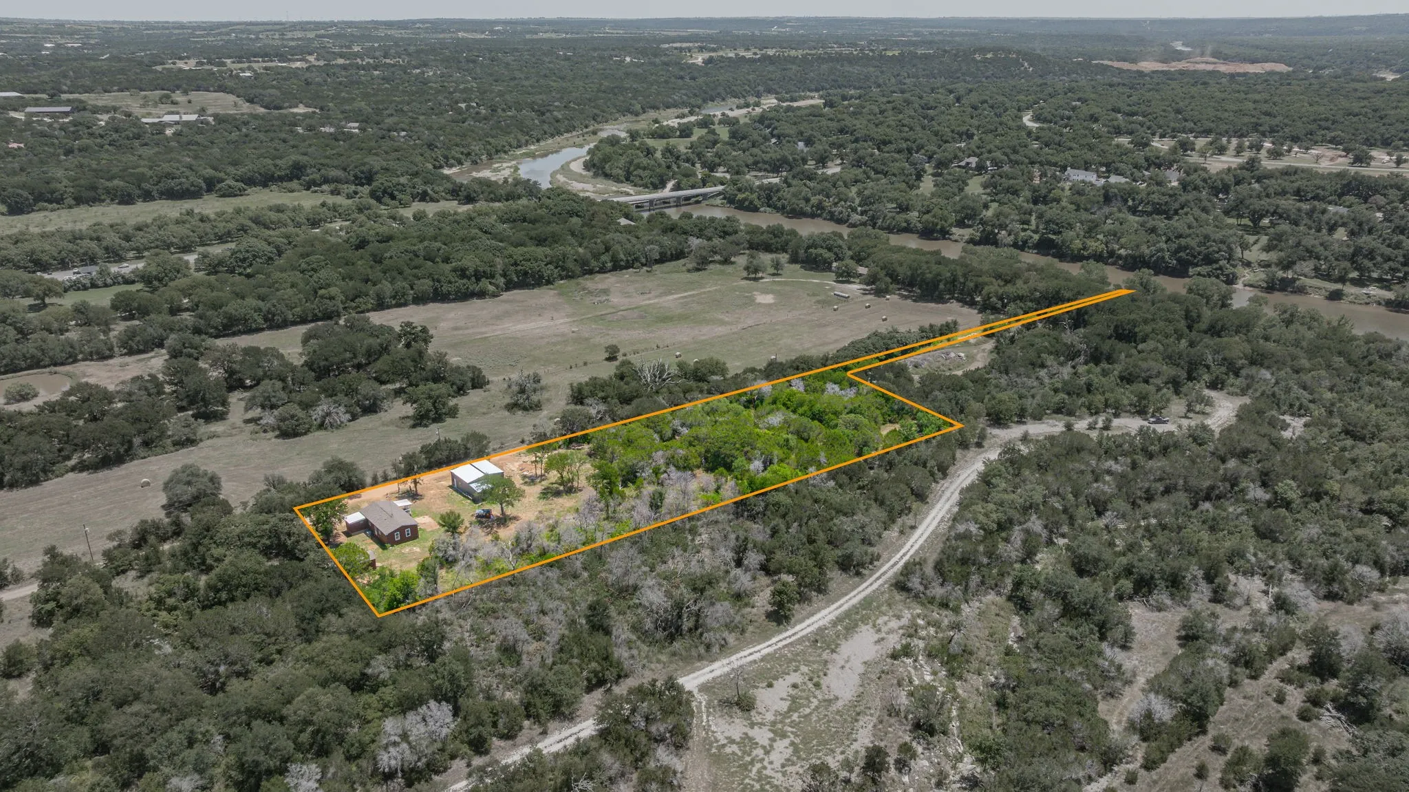 Expansive aerial view showcasing a large parcel of land with established trees and an open field