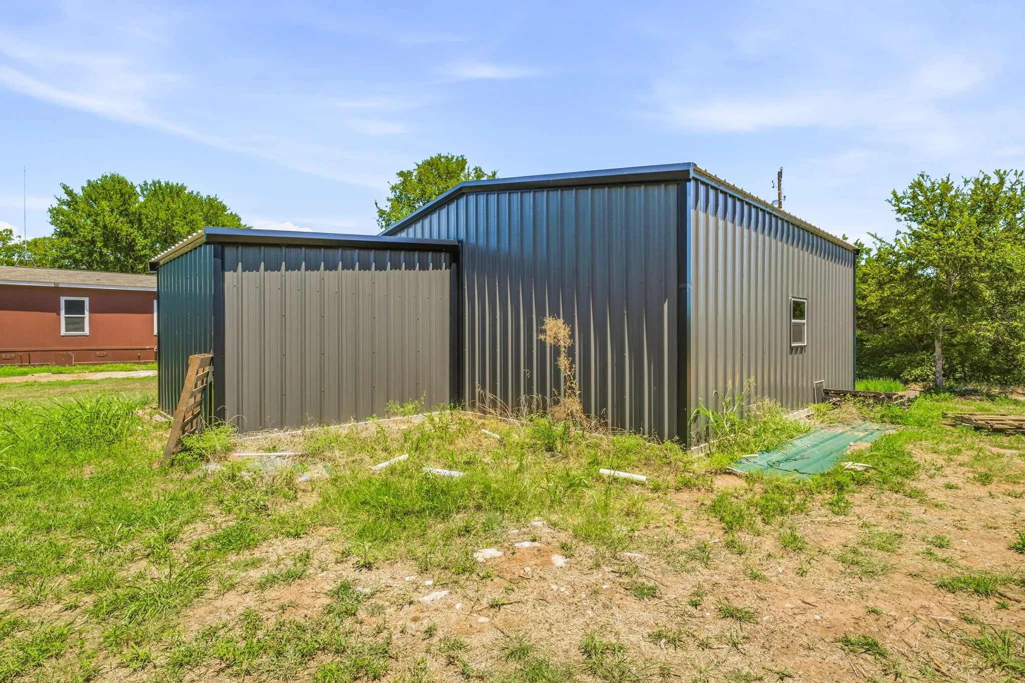 Metal utility building featuring a corrugated exterior, flat roofline, and an integrated smaller storage area