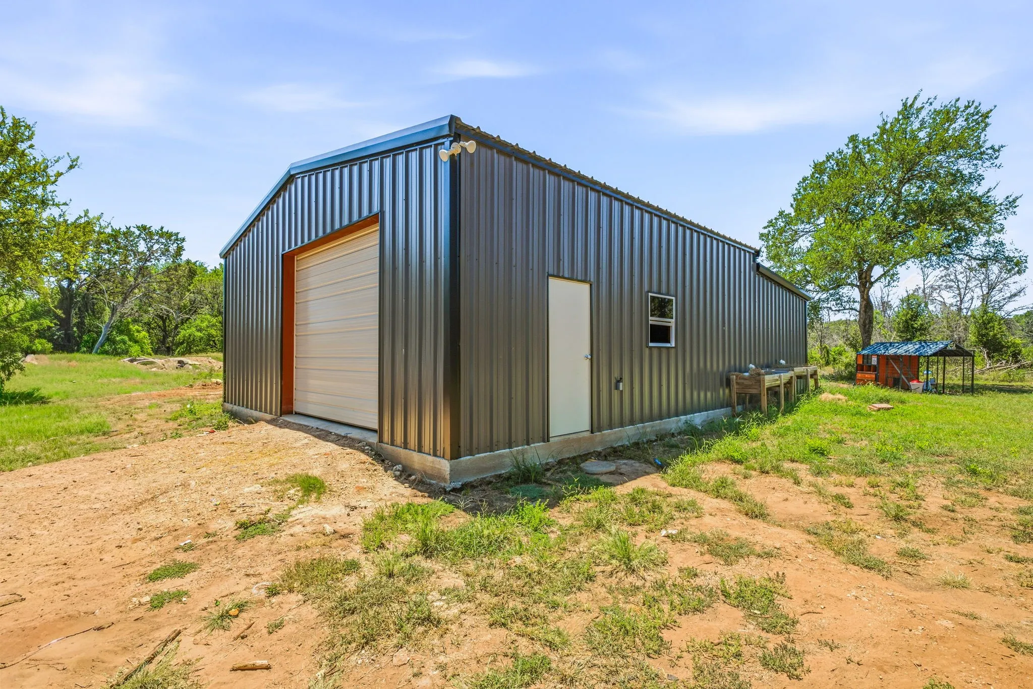 Metal utility building featuring a roll-up garage door, a side entry door, and a single window