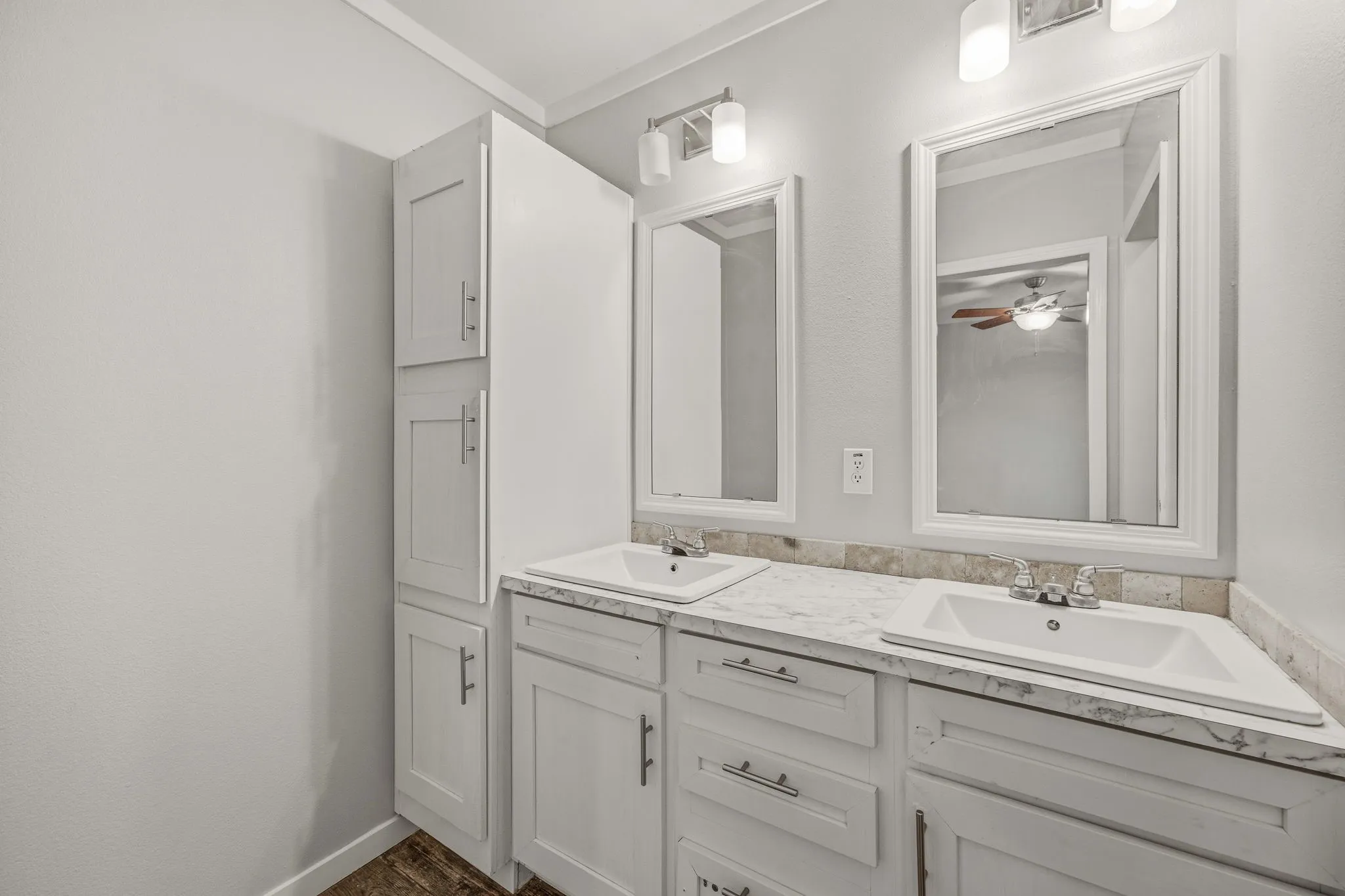 Dual vanity with white cabinetry, light-toned countertops, and two framed mirrors