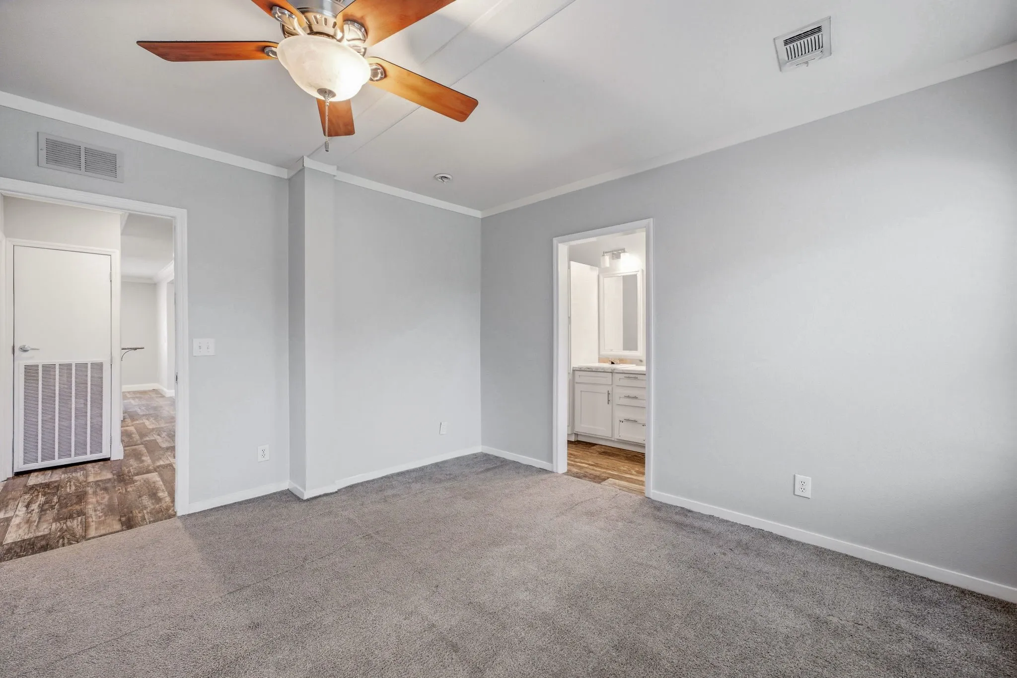Spacious room featuring light gray wall paint and gray carpeting