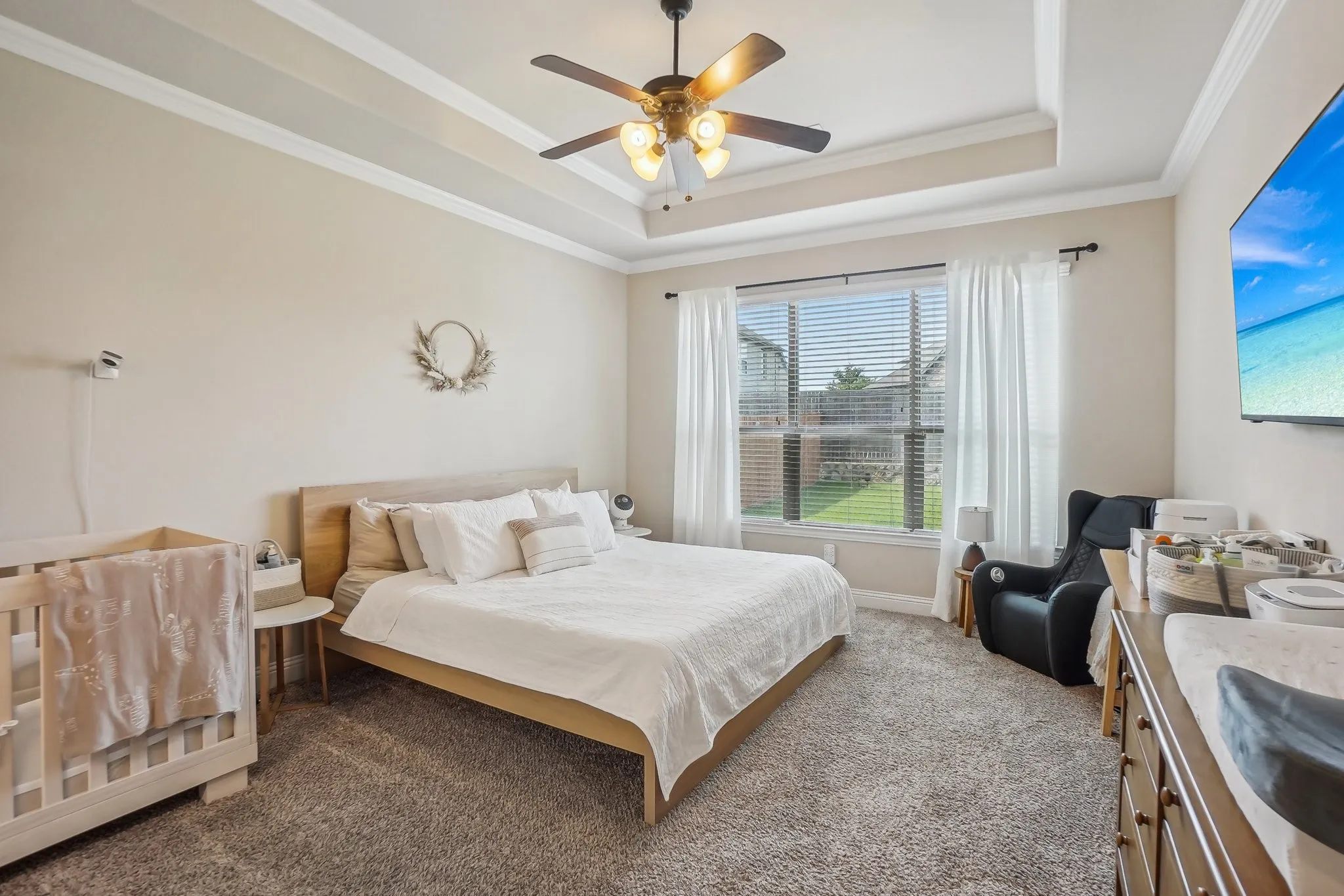 Bedroom featuring a tray ceiling, crown molding, a ceiling fan, and carpet floors