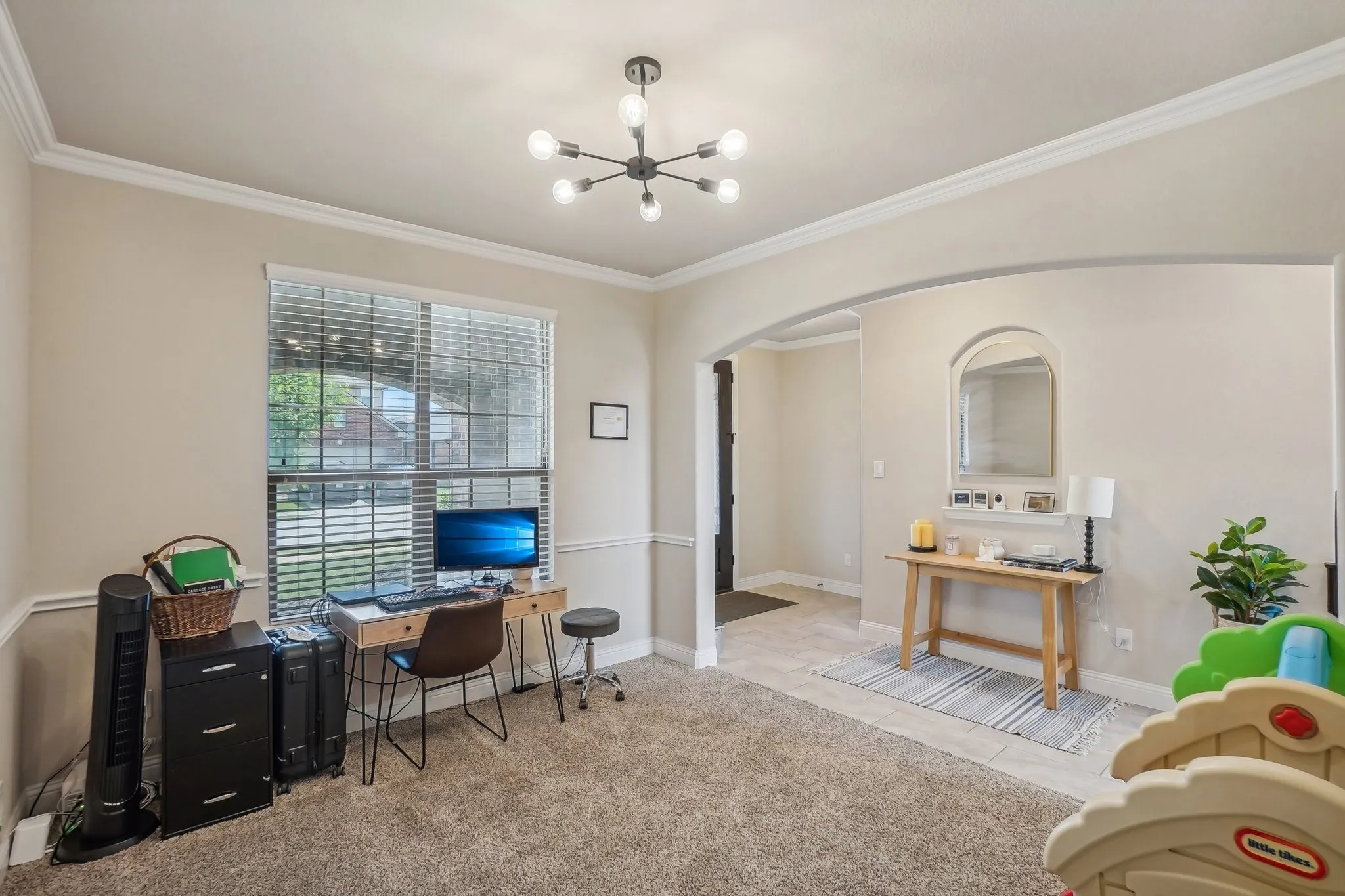 Carpeted office space featuring arched walkways, a chandelier, ornamental molding, and tile patterned flooring