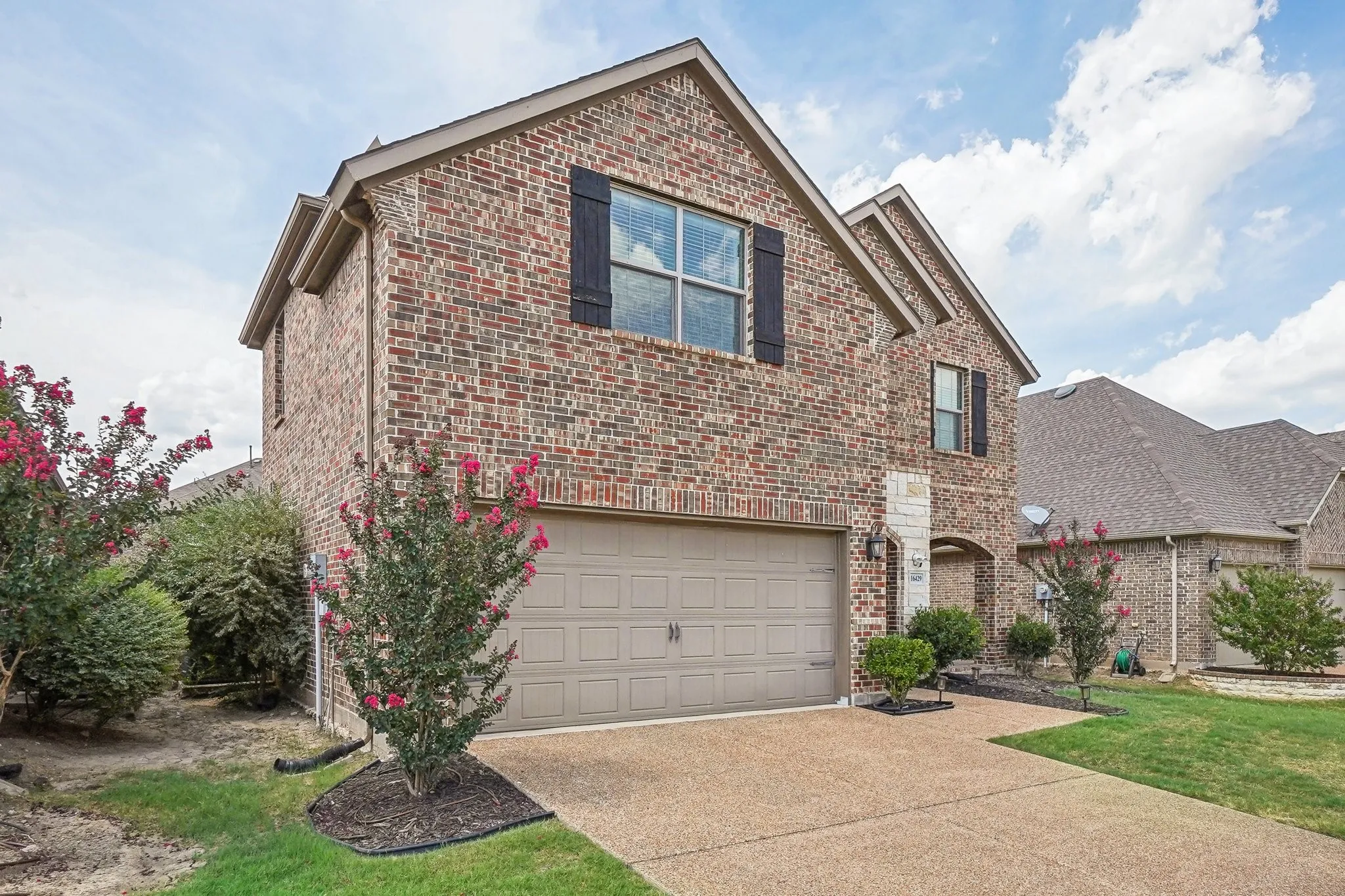 Traditional home with an attached garage, brick siding, and concrete driveway