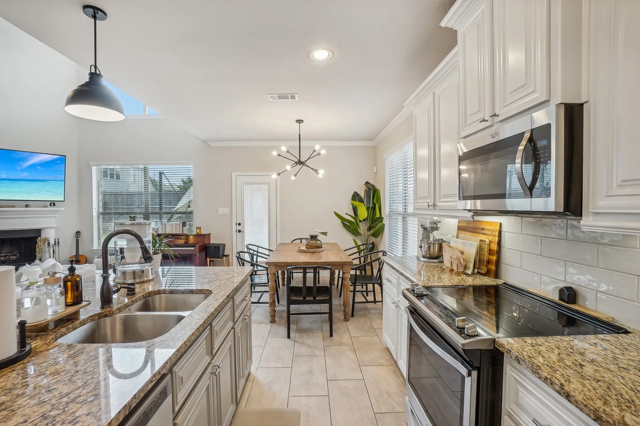 Kitchen with appliances with stainless steel finishes, light stone counters, hanging light fixtures, recessed lighting, and ornamental molding