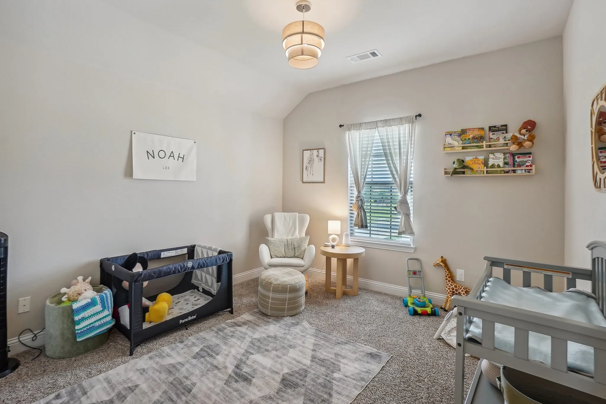 Carpeted bedroom featuring a nursery area and lofted ceiling