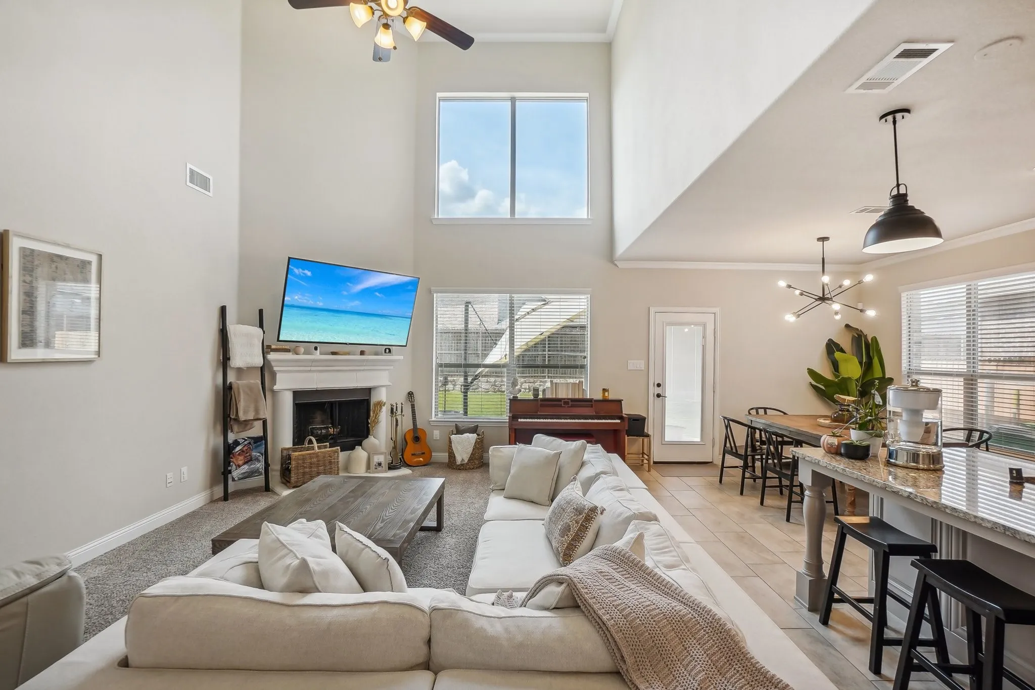 Living room with crown molding, plenty of natural light, a fireplace, a ceiling fan, and a towering ceiling