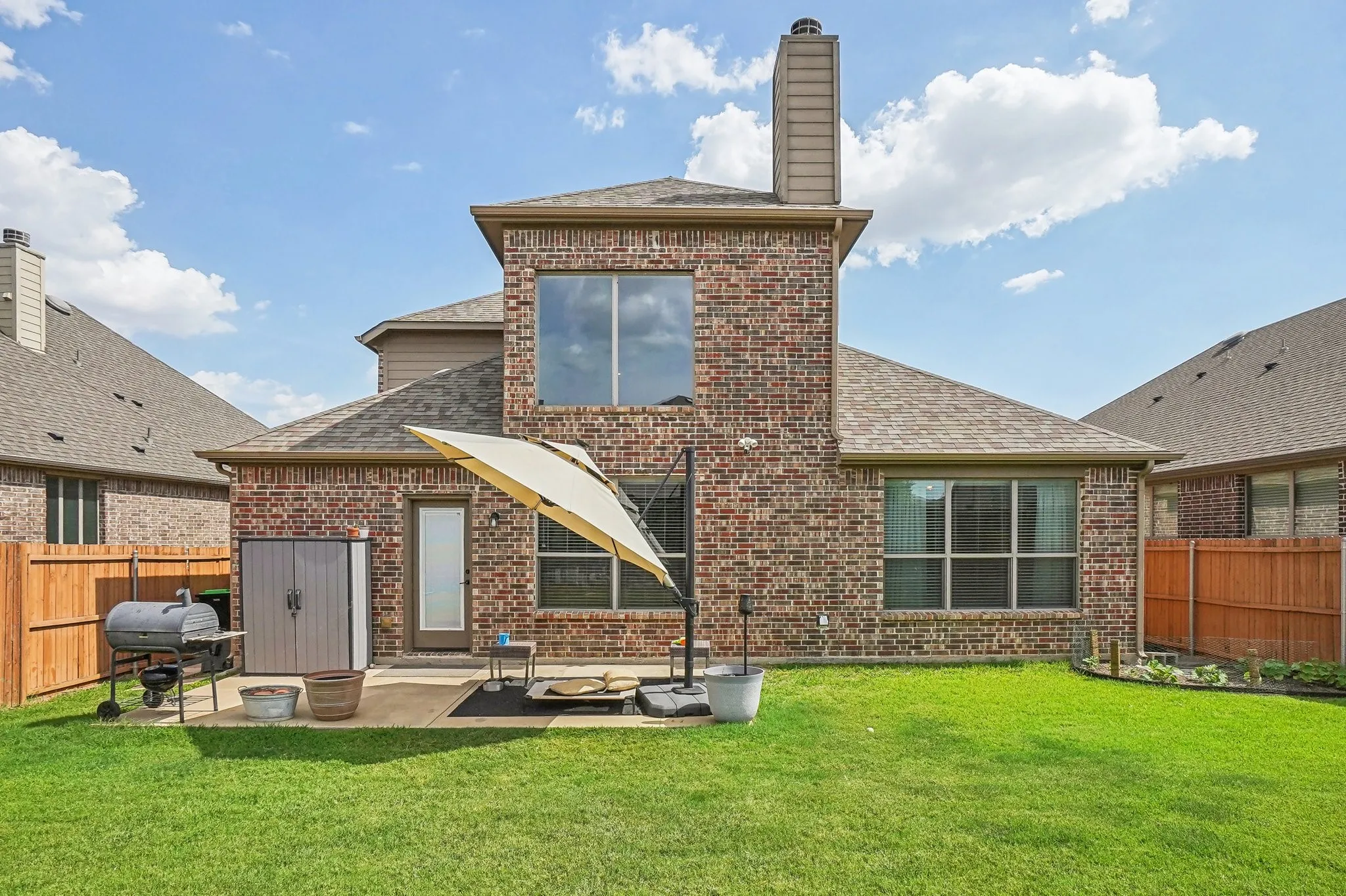 Rear view of house featuring a fenced backyard, brick siding, and a shingled roof