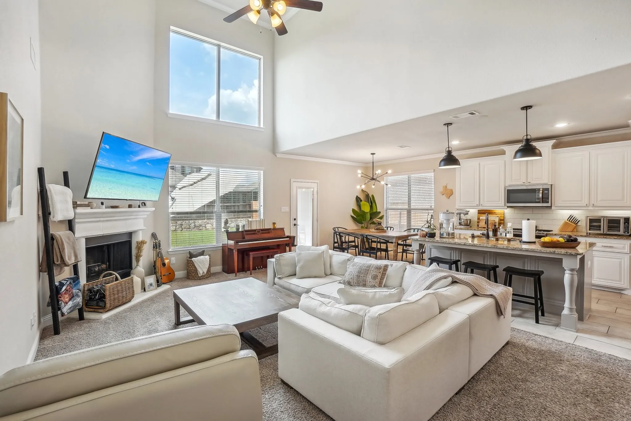 Living area featuring a fireplace, a chandelier, ornamental molding, a ceiling fan, and a towering ceiling