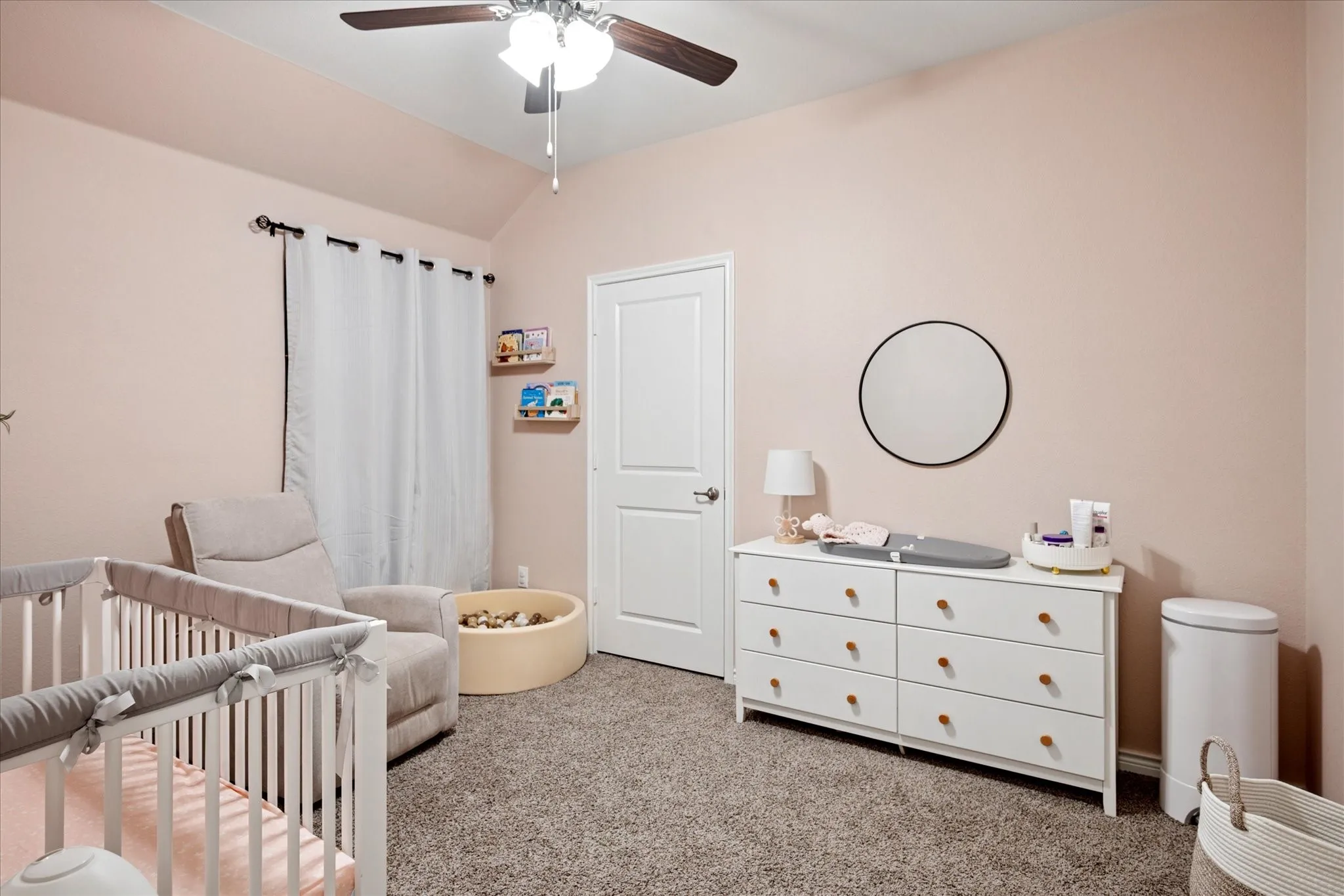 Carpeted room with a vaulted ceiling, a ceiling fan with integrated lighting, and a paneled white door