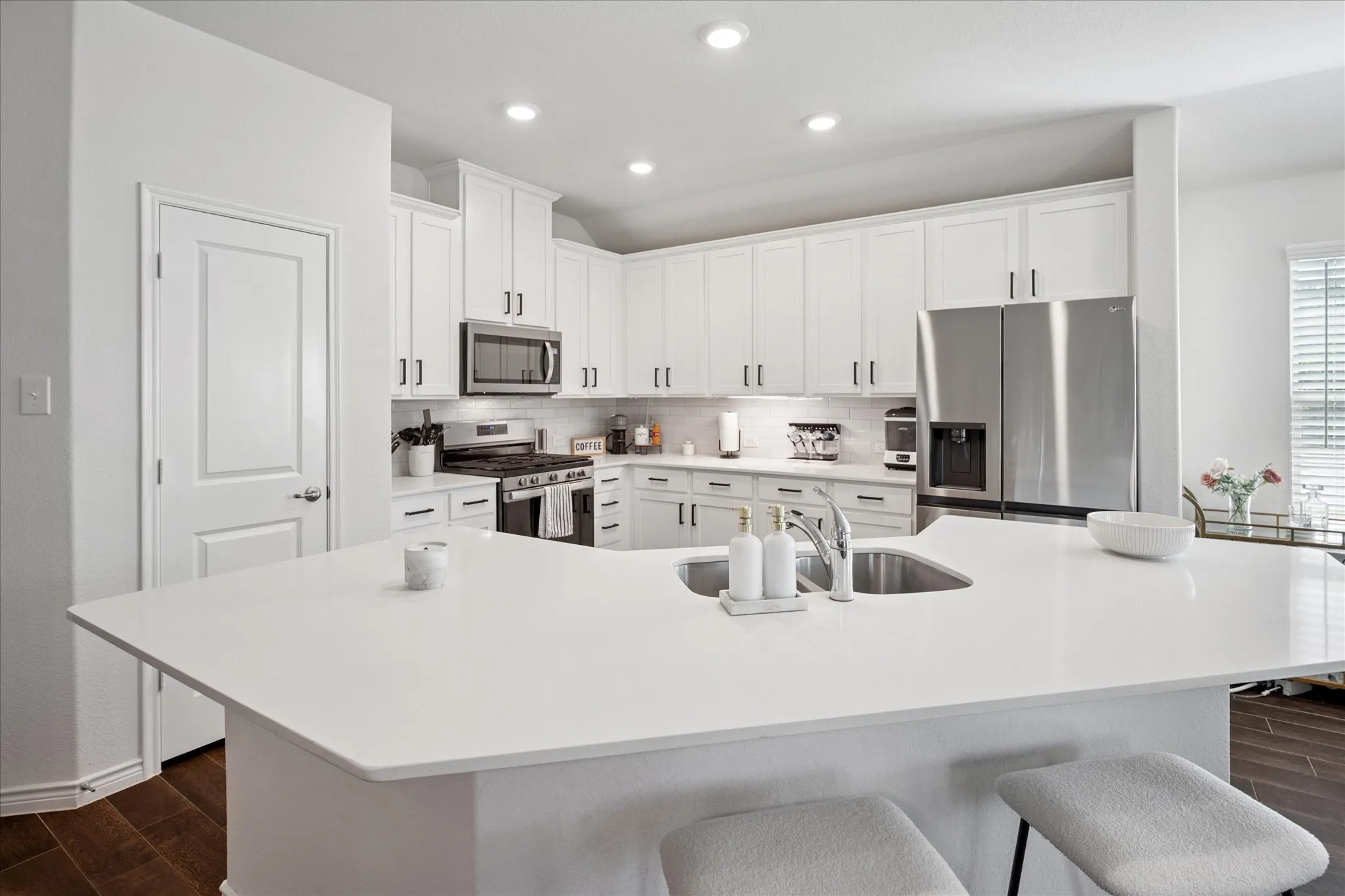 Modern kitchen with a large white island featuring an undermount stainless steel sink