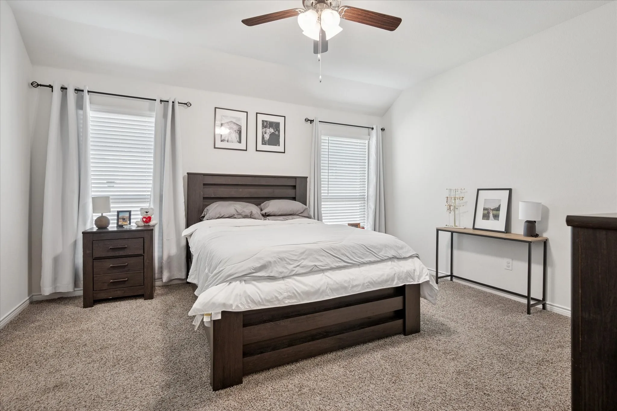 Carpeted bedroom featuring a vaulted ceiling and a ceiling fan with integrated lighting