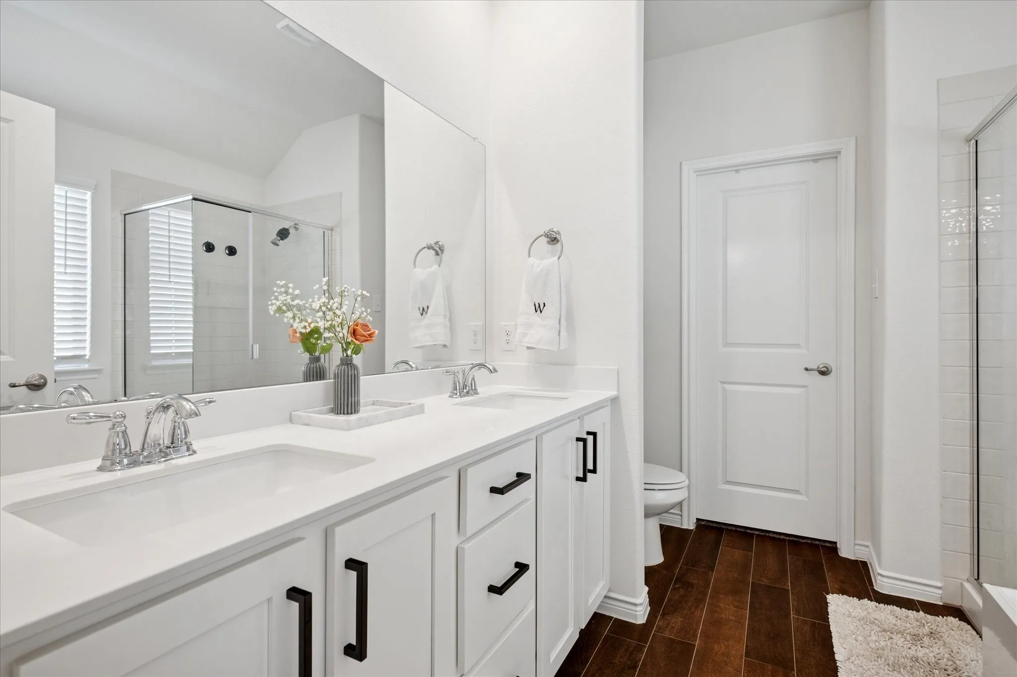 Dual vanity with white cabinetry and black hardware, complemented by chrome faucets