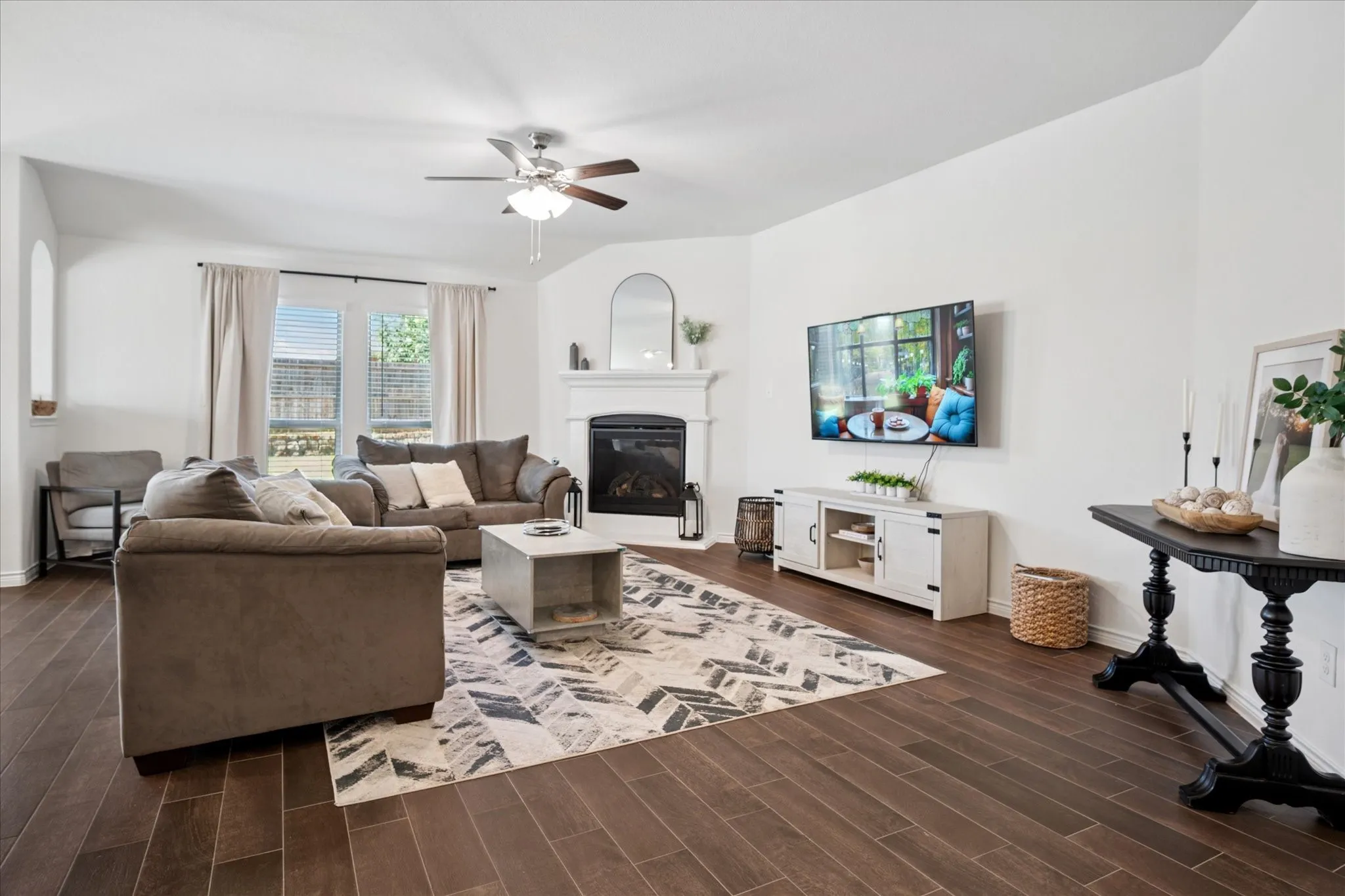 Spacious living area featuring wood-finish flooring, a ceiling fan, and white walls