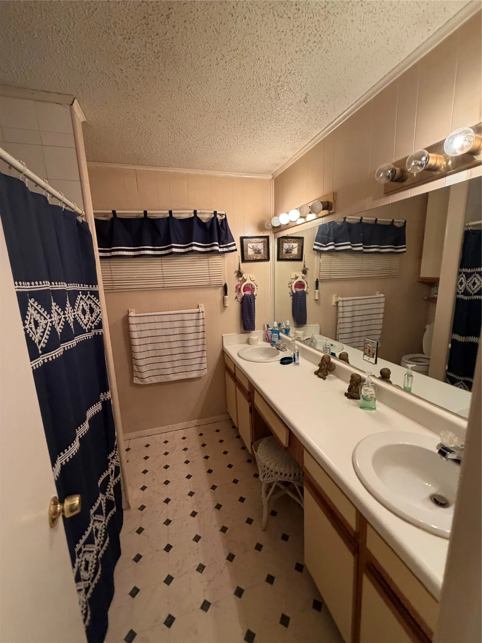 Dual vanity with integrated sinks, expansive counter space, large mirror, and patterned flooring
