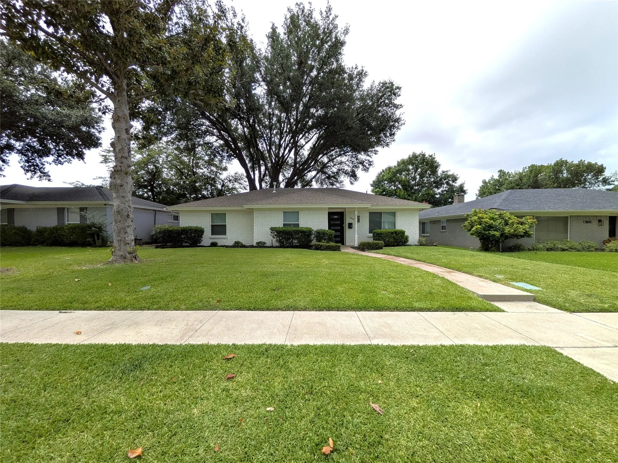 Single-story residence featuring a white brick exterior, dark entry door, and a light-colored roof
