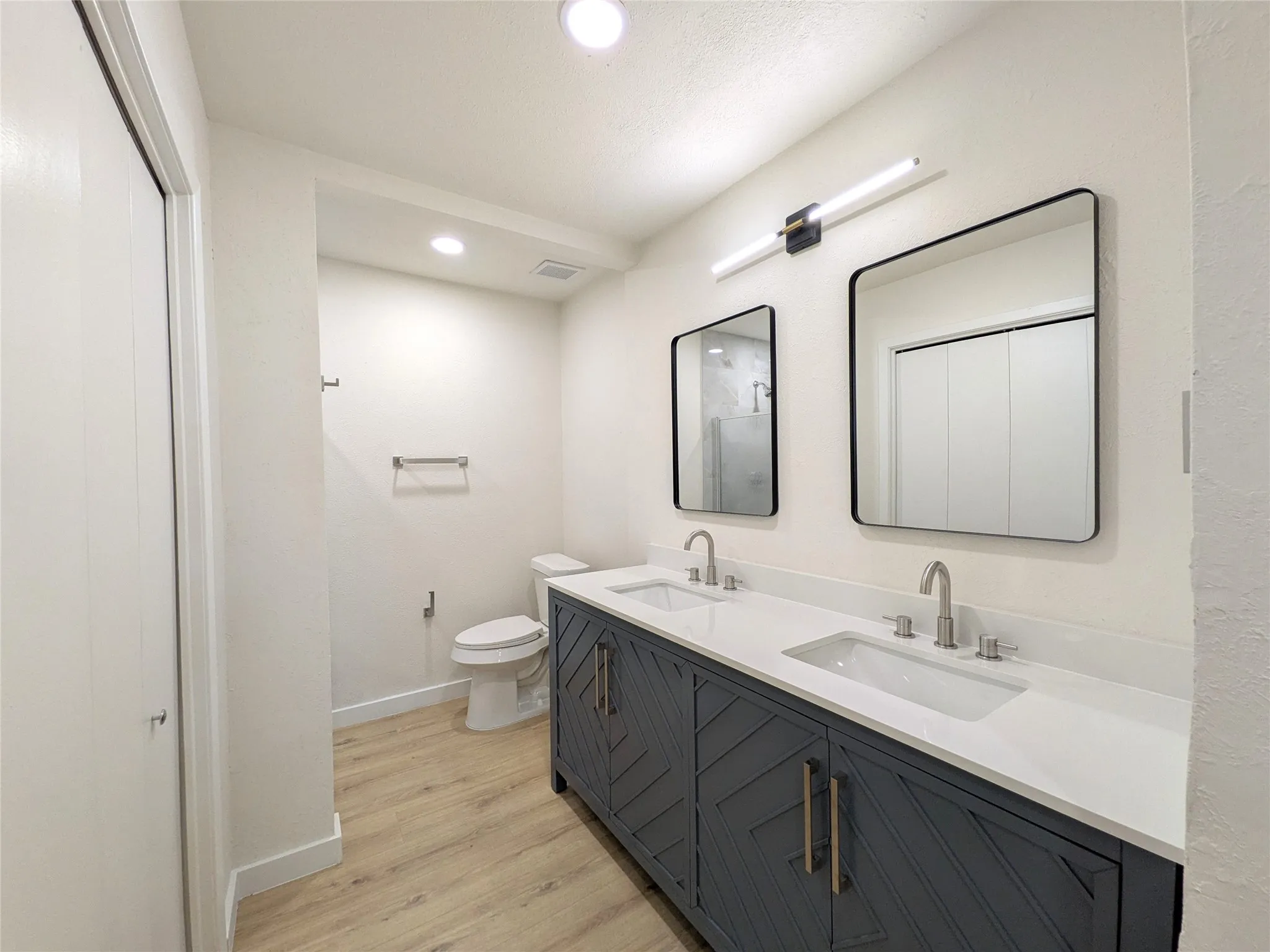 Bathroom featuring a double vanity with dark blue cabinetry, white countertops, and dual undermount sinks