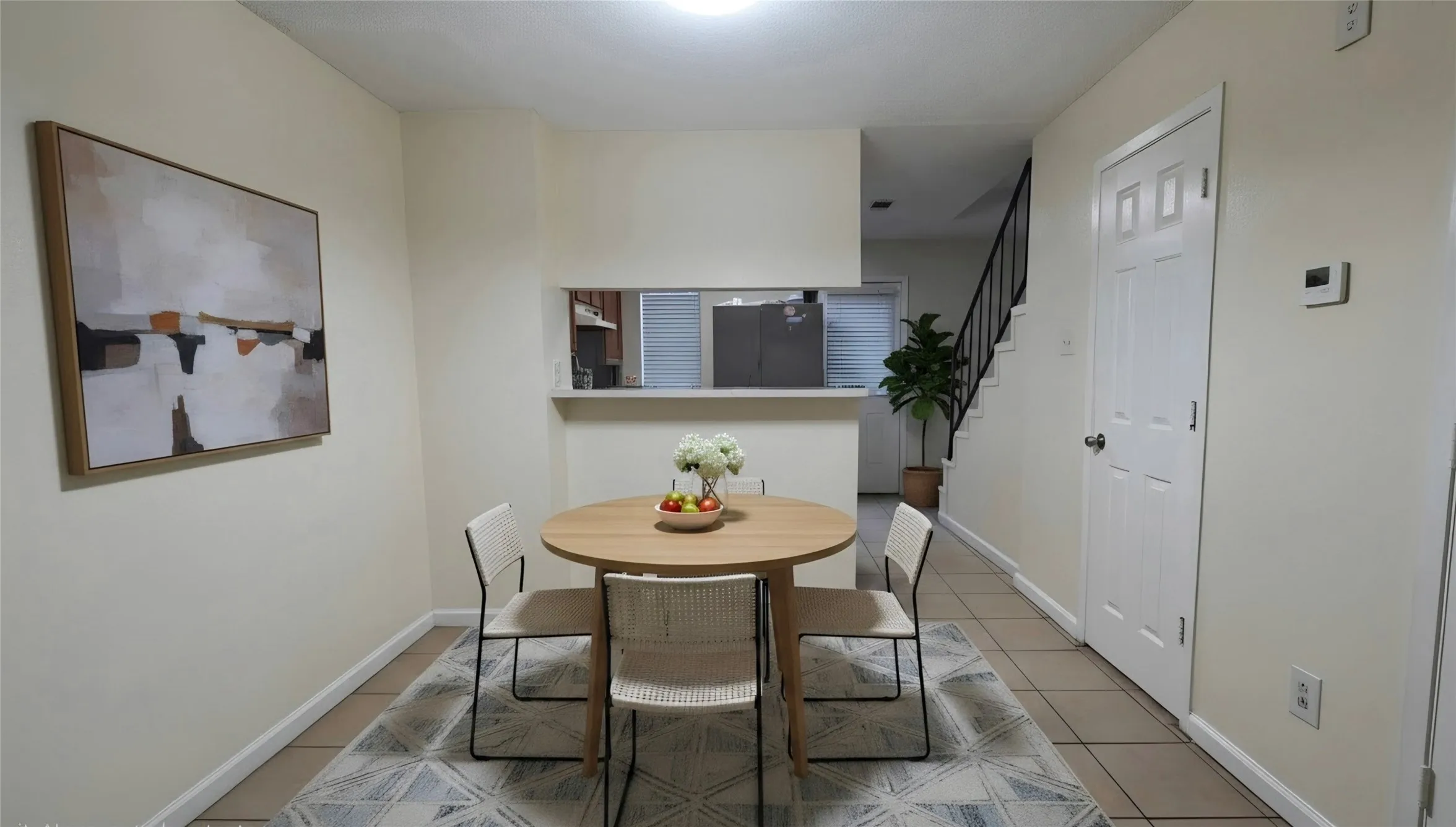 Dining area featuring light-toned walls, tile flooring, and a pass-through window with a breakfast bar