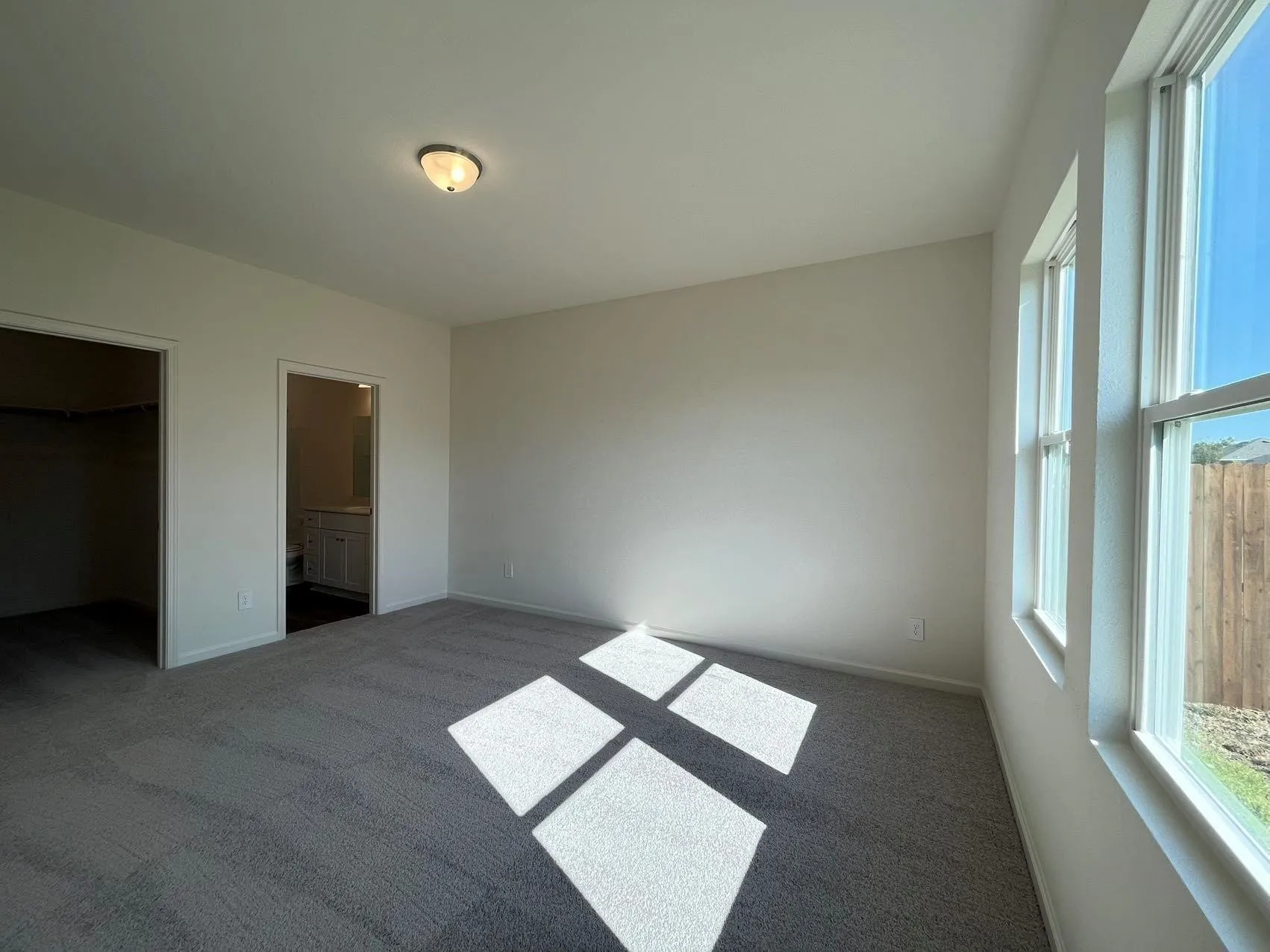 Unfurnished bedroom with carpet floors, a walk in closet, and ensuite bath