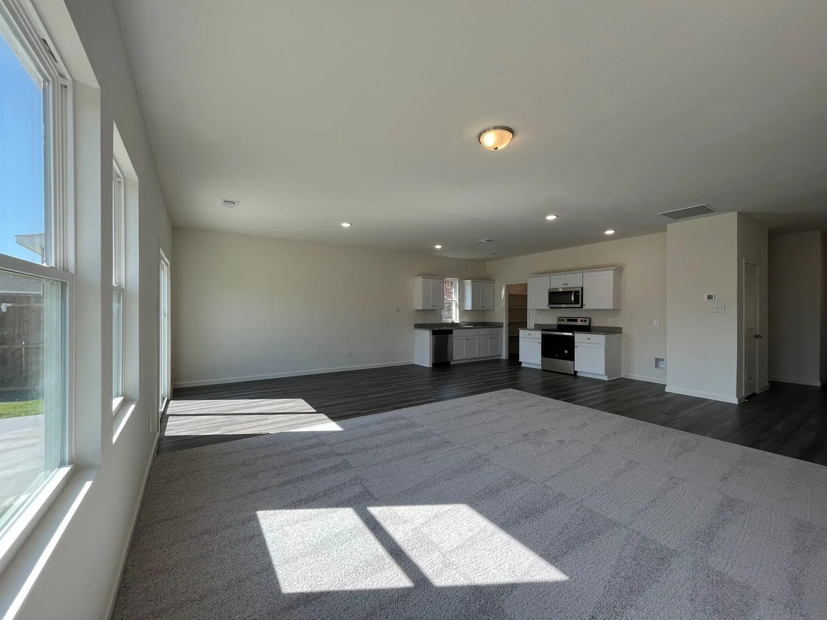 Unfurnished living room with healthy amount of natural light, recessed lighting, and dark colored carpet
