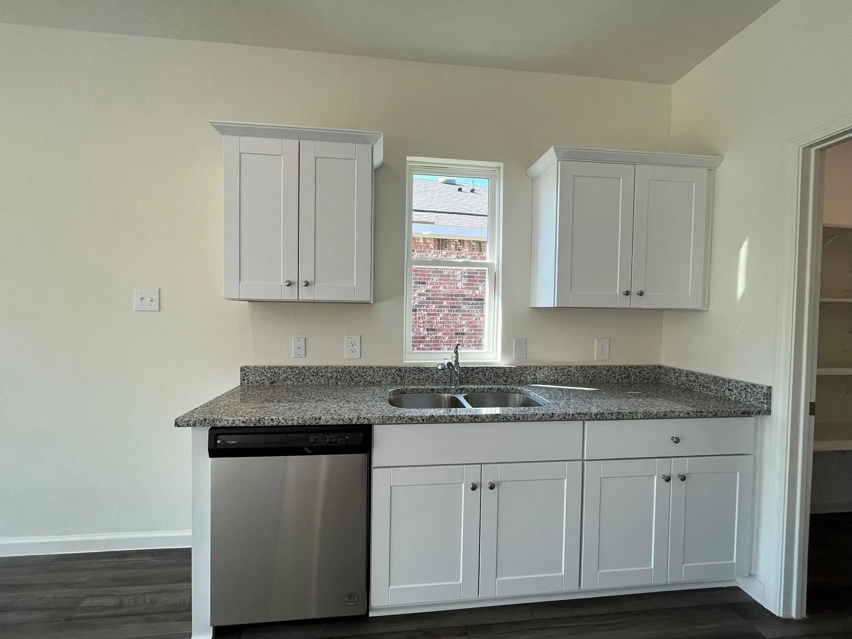 Kitchen featuring white cabinets, dishwasher, dark stone countertops, and dark wood-style floors