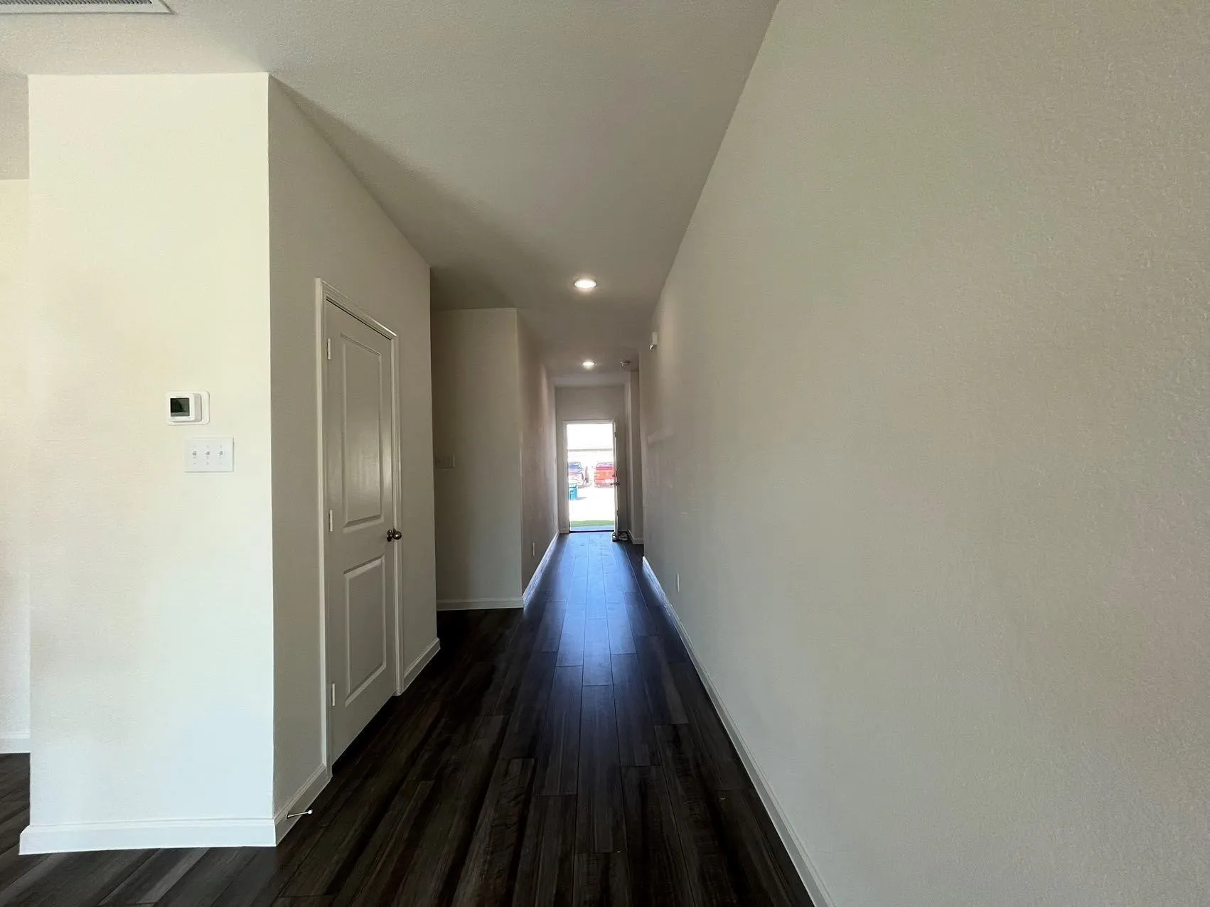 Corridor with dark wood-style flooring and recessed lighting