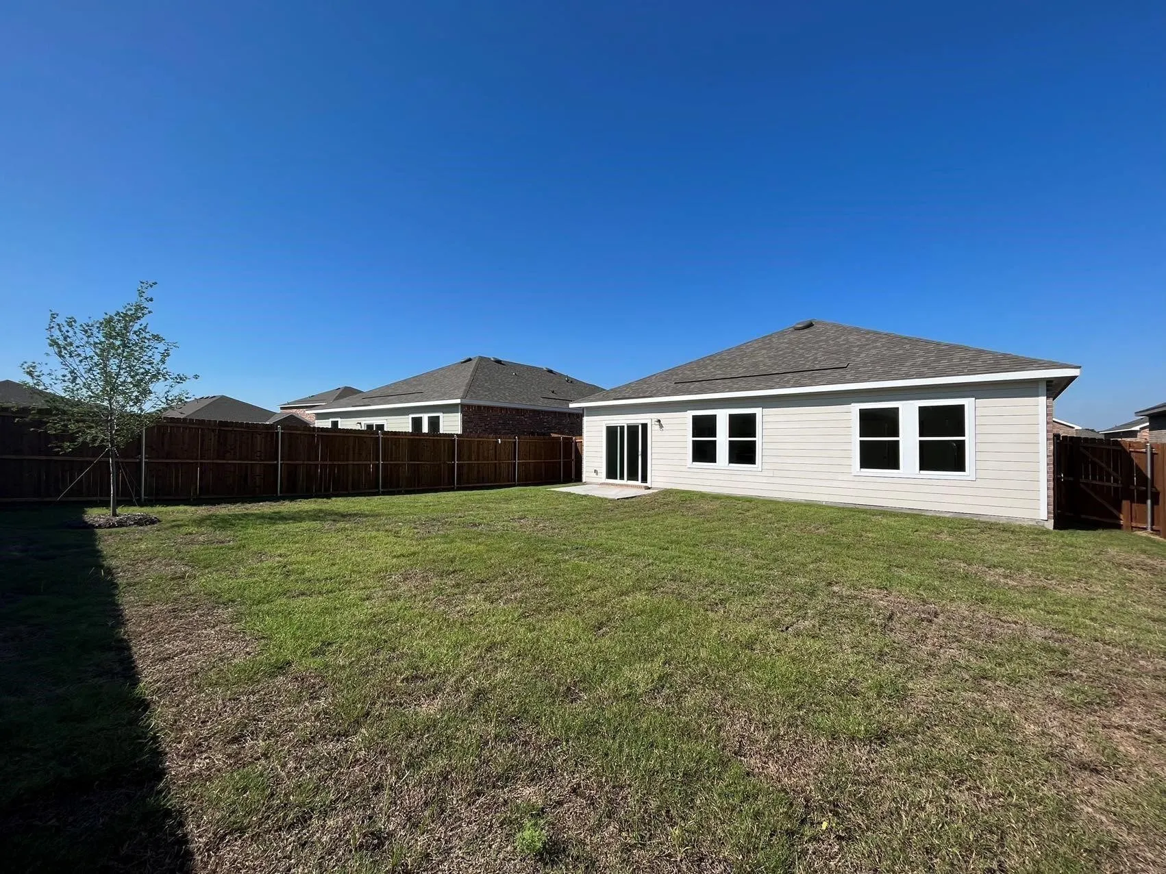 Back of house featuring a patio, a fenced backyard, and a shingled roof