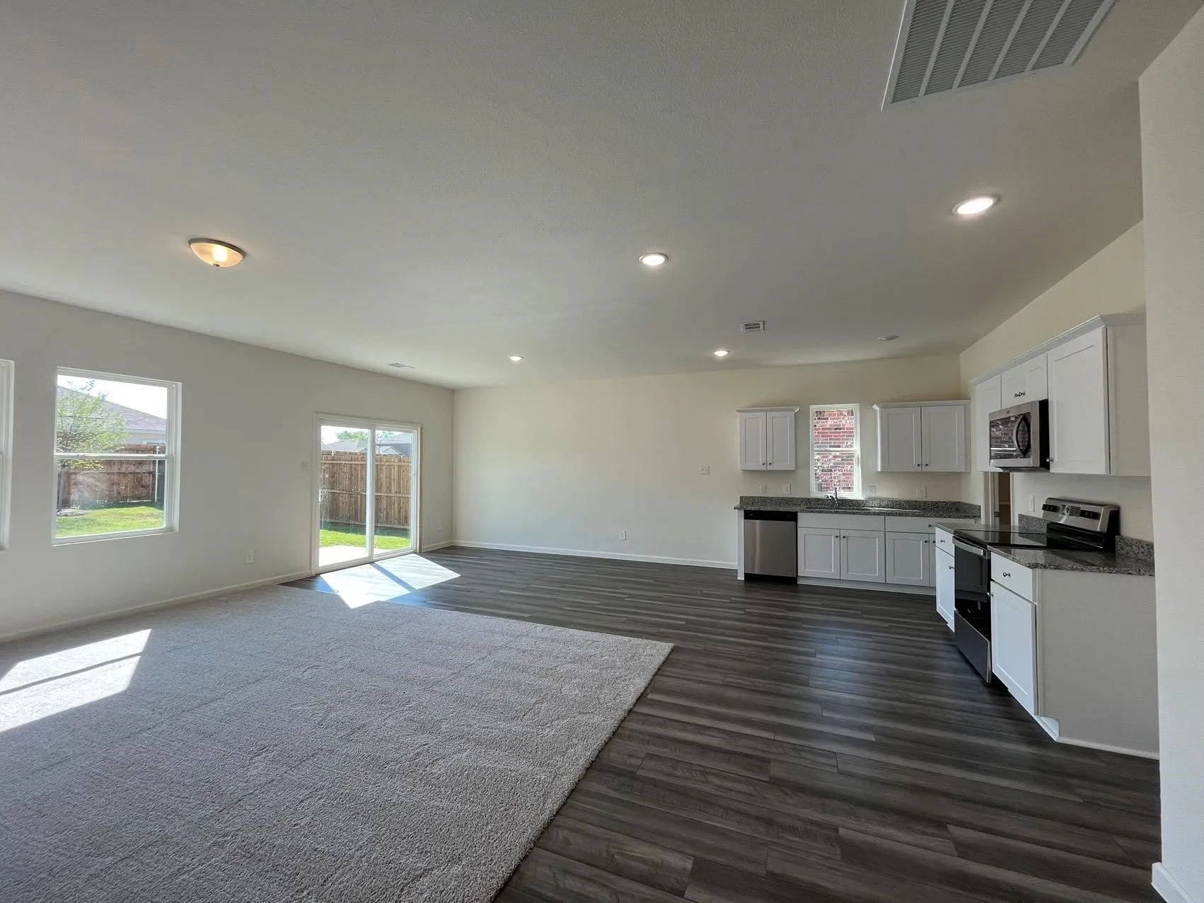 Kitchen with white cabinetry, stainless steel appliances, open floor plan, recessed lighting, and dark wood-style floors