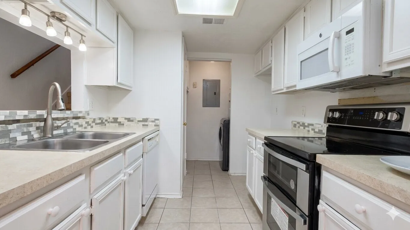 Galley kitchen featuring white cabinetry, light-toned countertops, and a mosaic tile backsplash