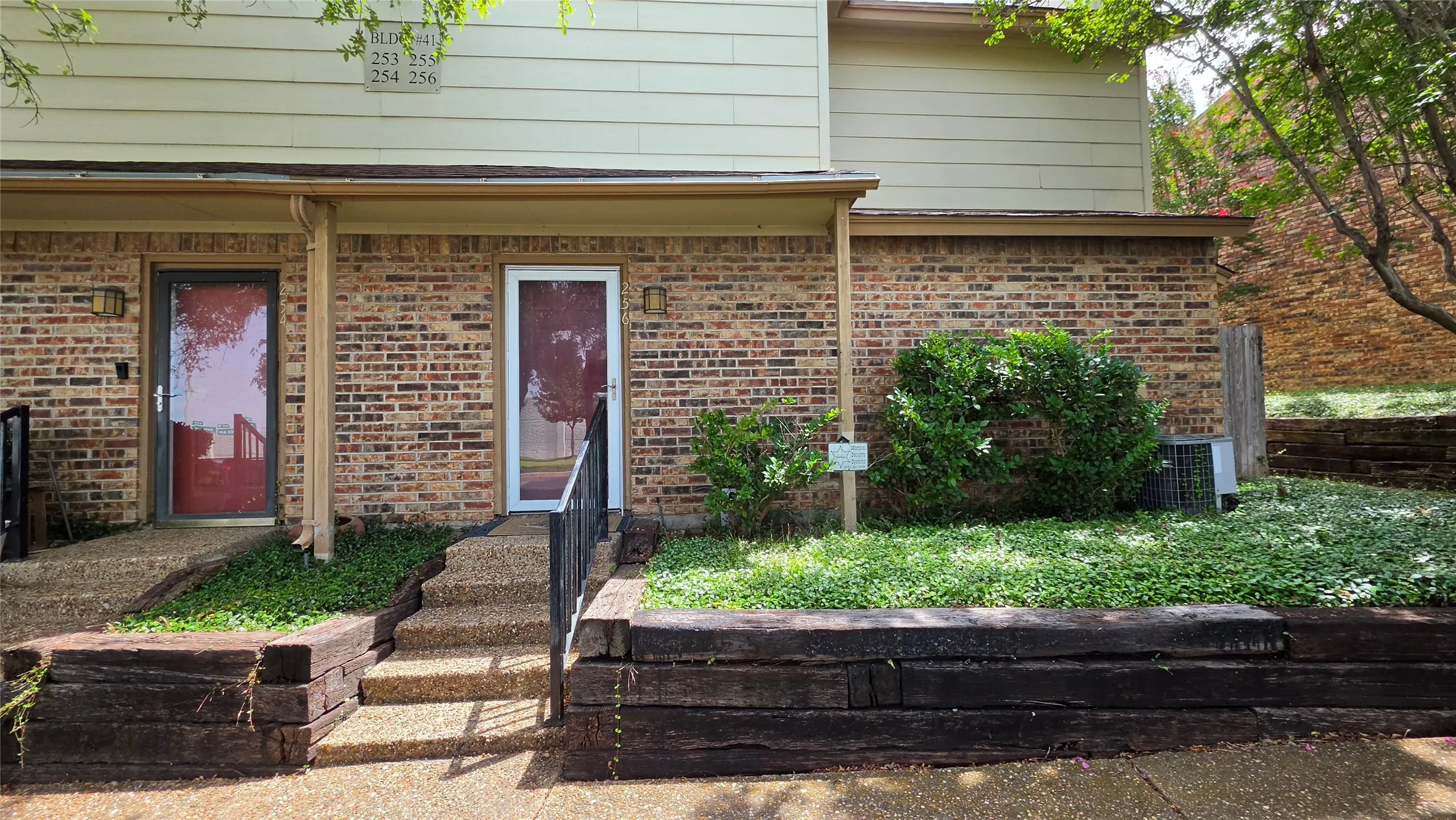 Brick facade entry with dual doorways, each featuring a storm door