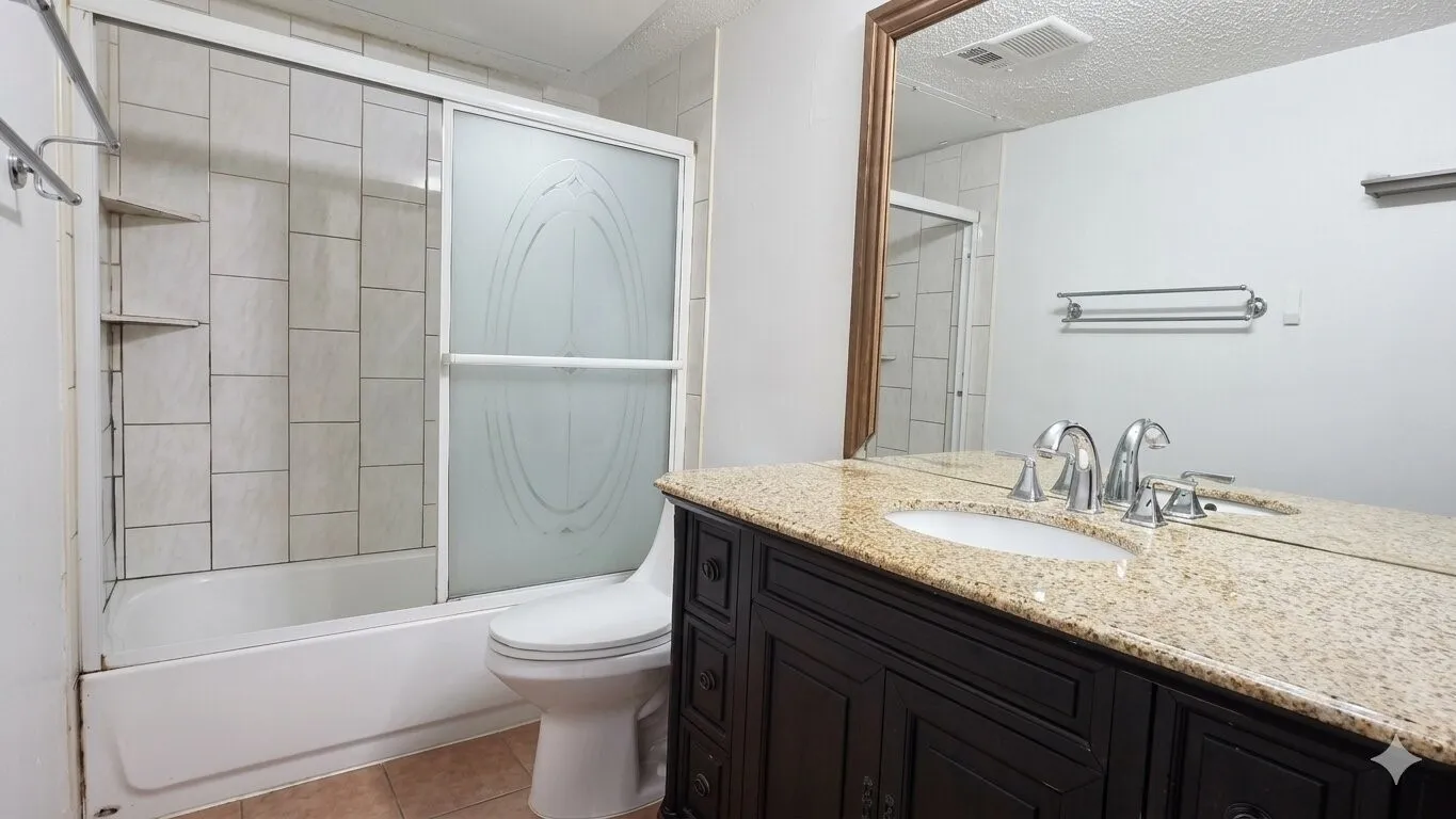 Bathroom featuring a dark wood-finish vanity with a light speckled countertop, an undermount sink, and a chrome faucet