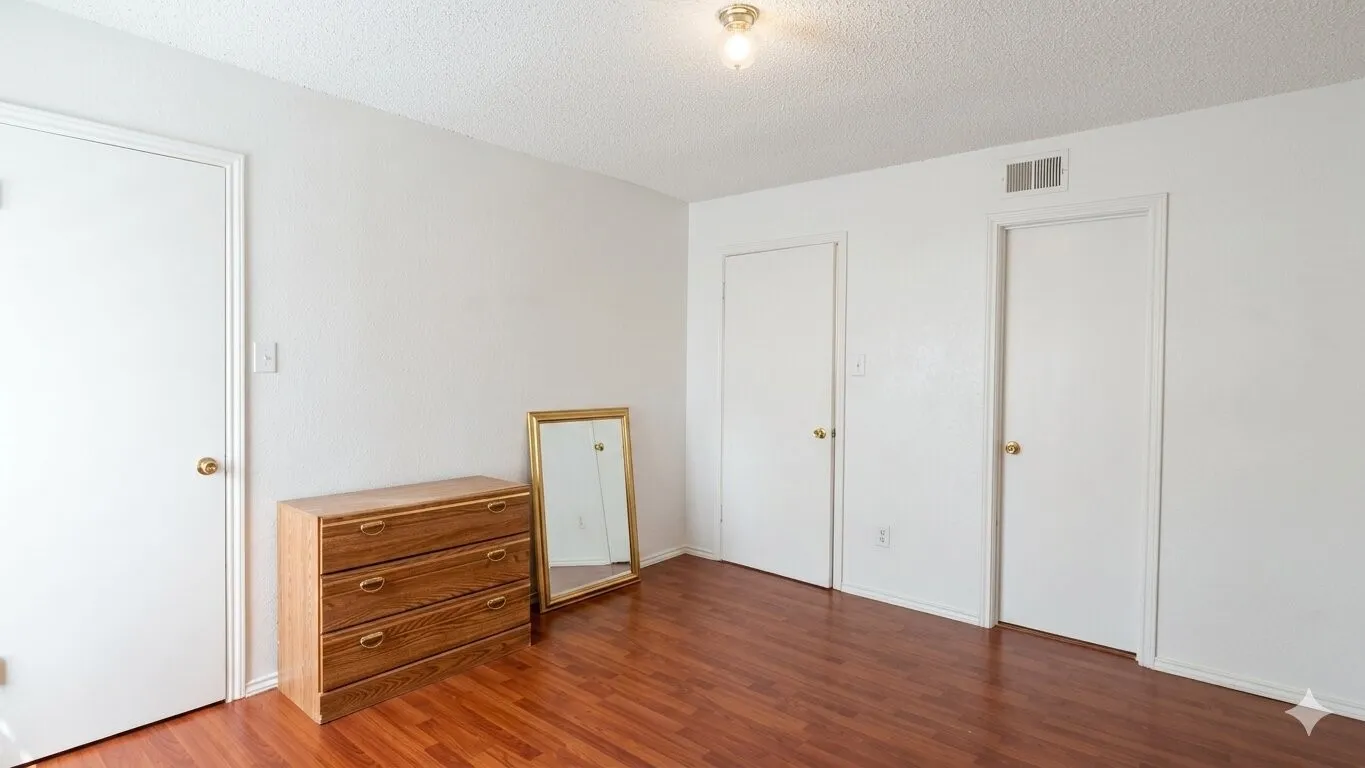 Interior room featuring wood-finish flooring, white painted walls, and a textured ceiling