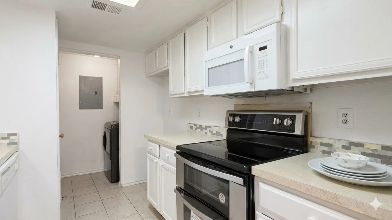 White cabinetry with built-in microwave, tiled backsplash, and light-colored countertops