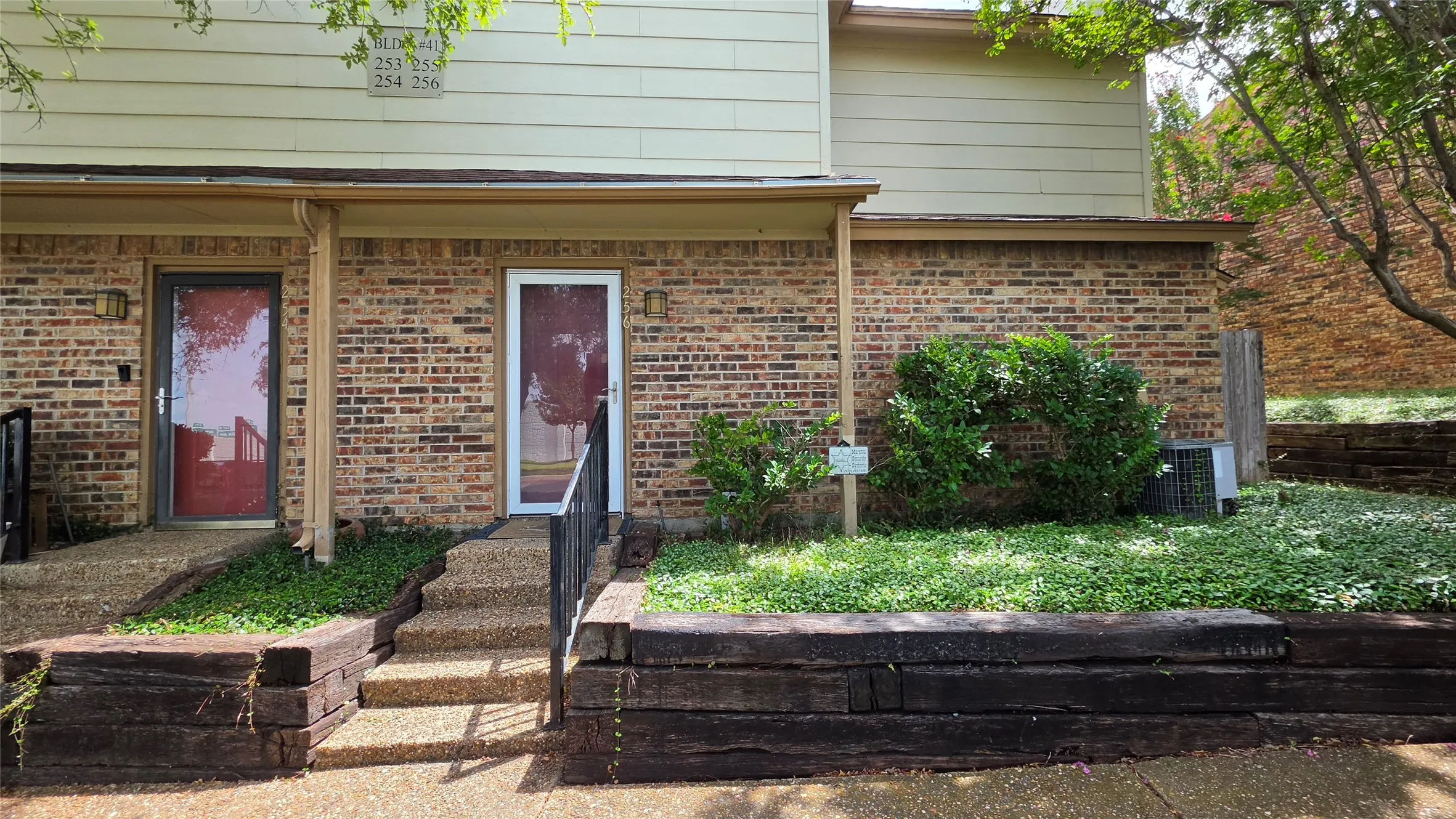 Brick facade with two entryways featuring storm doors and exterior lighting fixtures