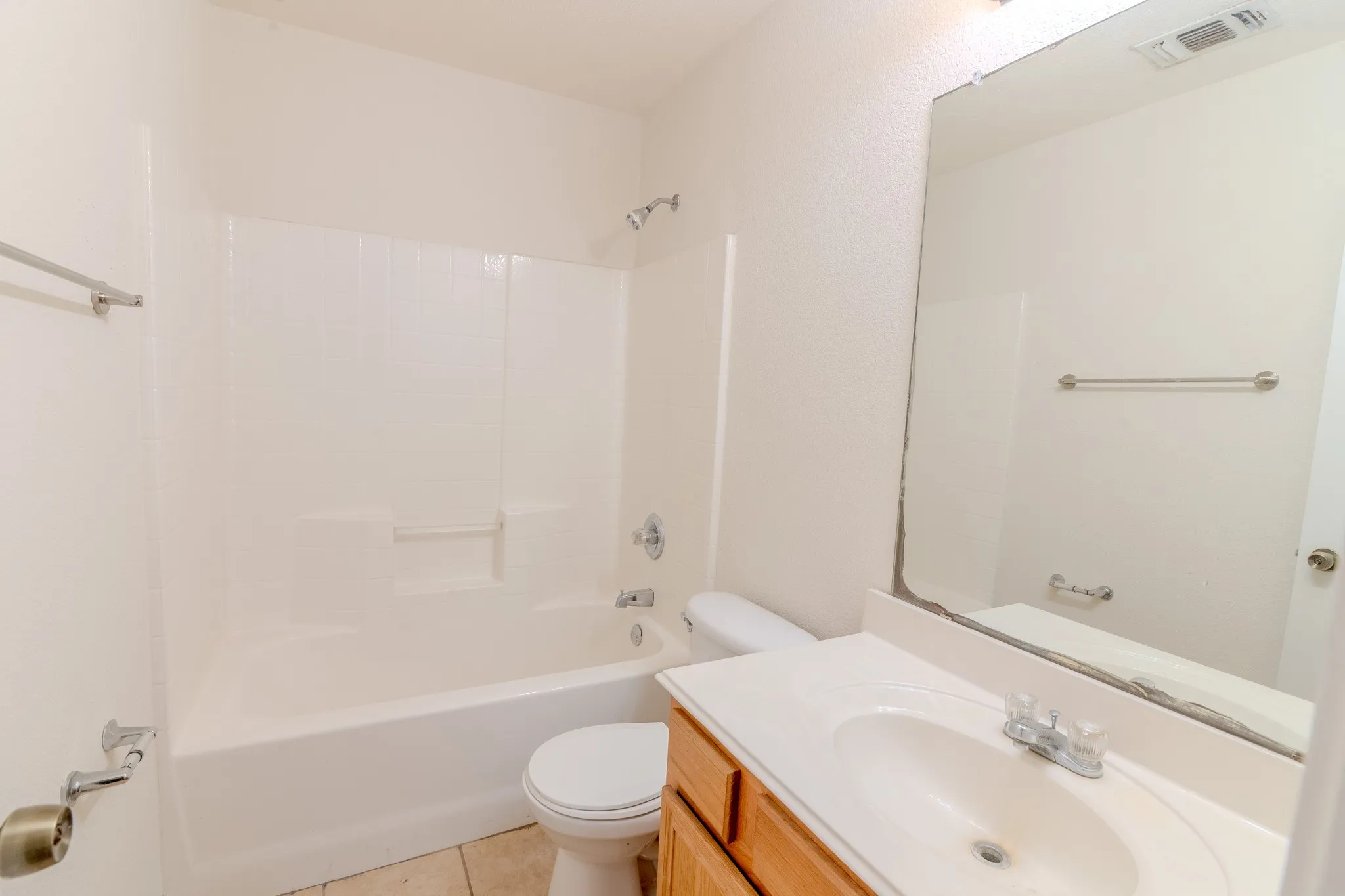 Bathroom featuring a full-size bathtub with shower combination, single vanity with integrated sink, wood-finish cabinetry, and a large wall-mounted mirror