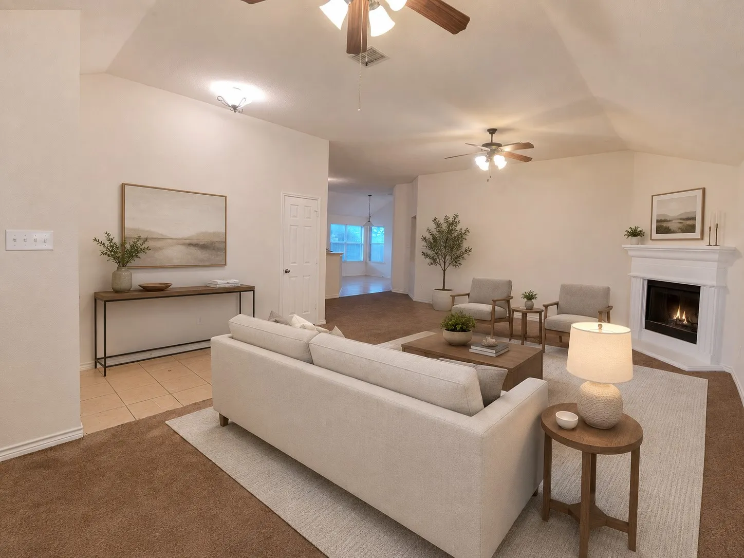 Virtually Staged Spacious living area featuring a fireplace with a white mantel, vaulted ceiling, and multiple ceiling fans