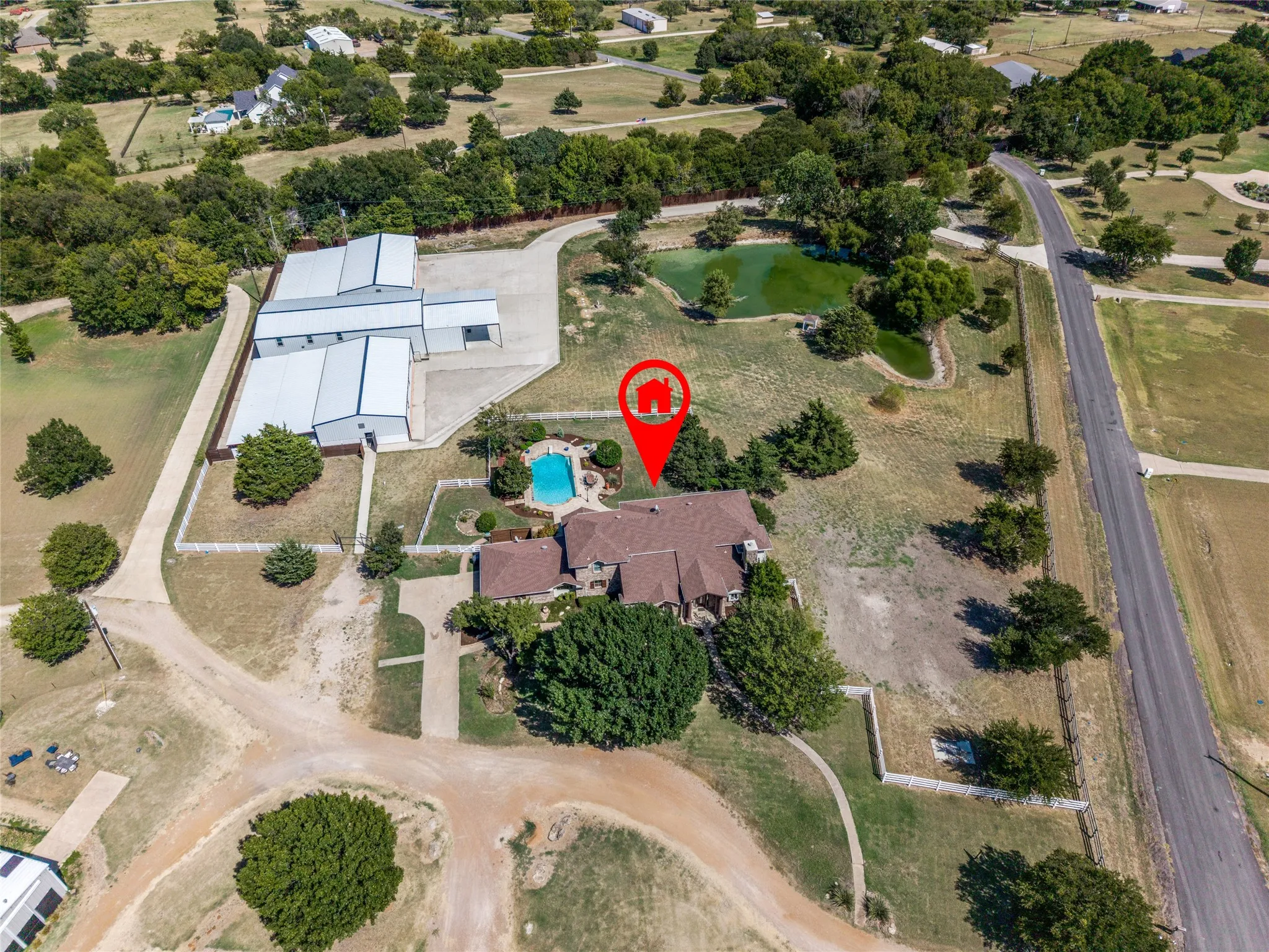 Extensive property with a main residence, an outdoor swimming pool, a large outbuilding, and a pond