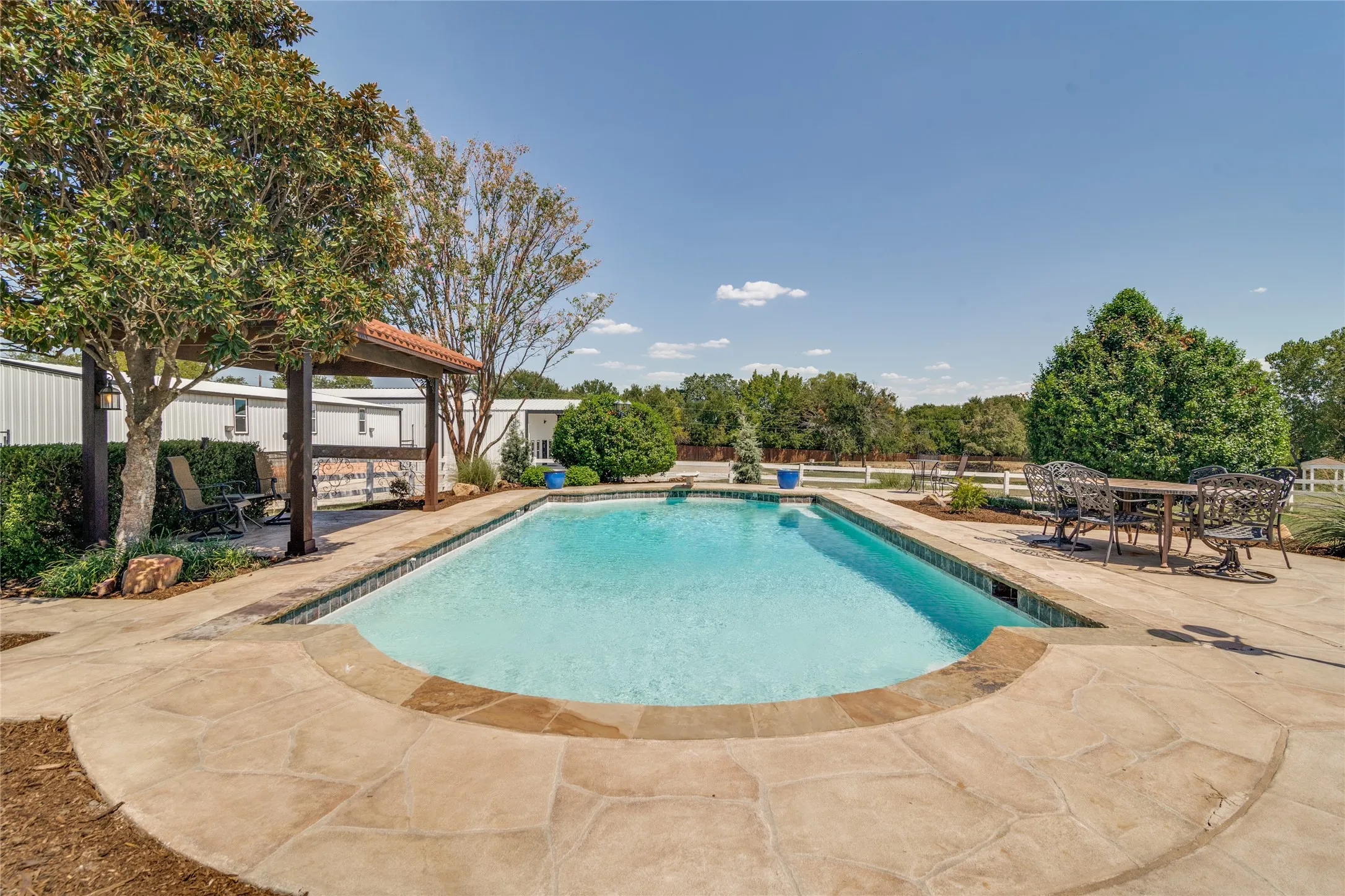 Resort-style pool with flagstone paving surround, a dedicated pergola, and perimeter landscaping