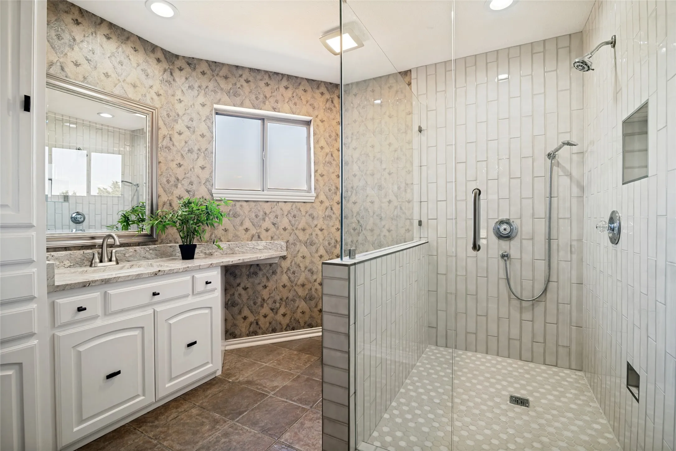 Glass-enclosed shower with vertical subway tile, a built-in niche, and a contrasting textured floor