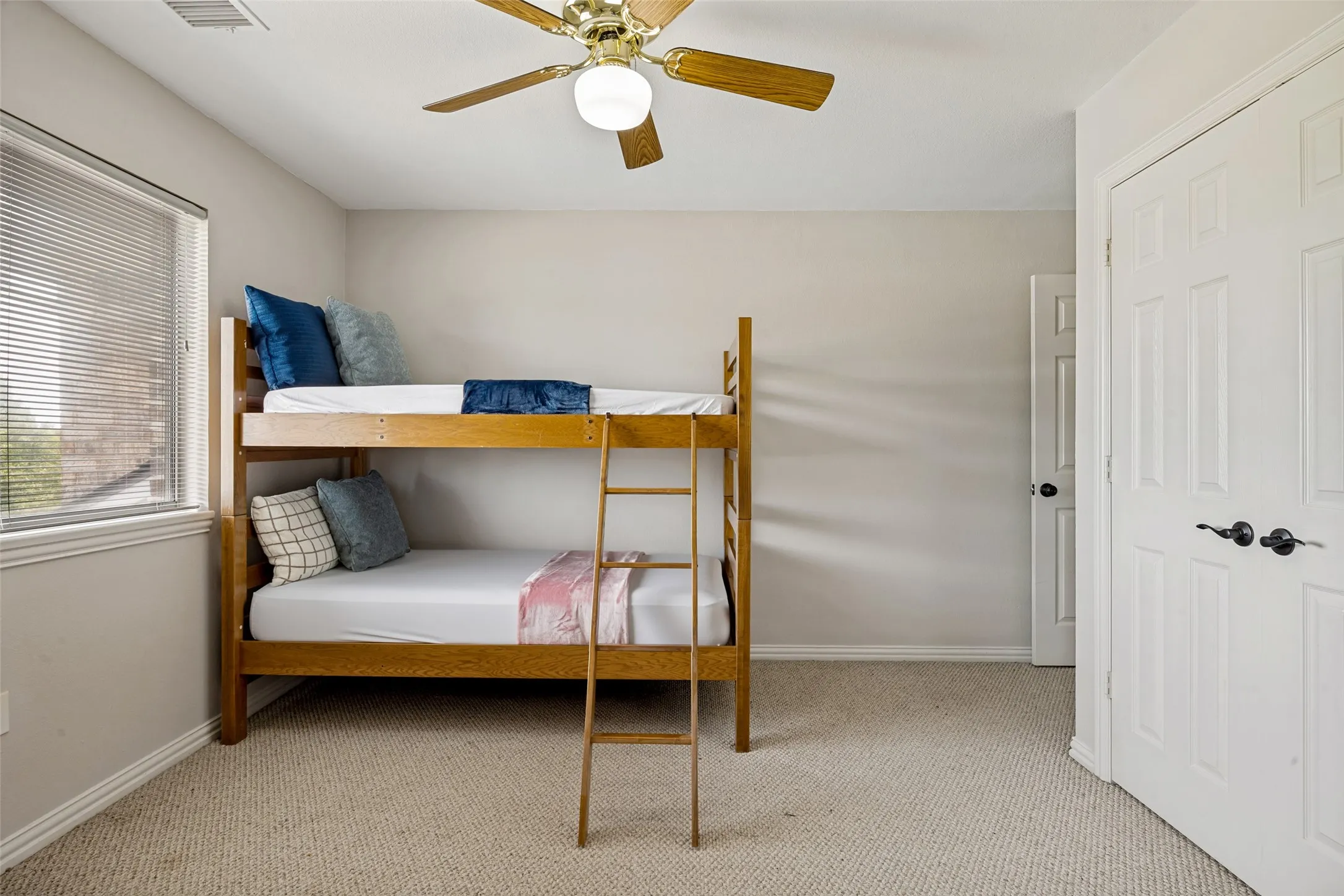 Split Bedroom featuring neutral wall paint, textured carpet flooring, a window with blinds, and a brass-finish ceiling fan with integrated lighting. Adjacent to Jack & Jill bathroom with large shower