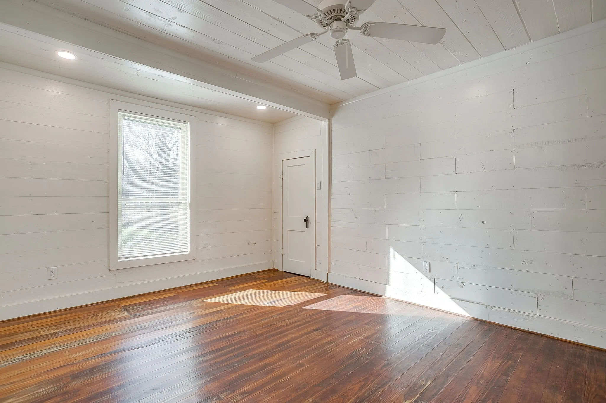 Spare room featuring hardwood / wood-style floors, wood ceiling, concrete block wall, and a ceiling fan