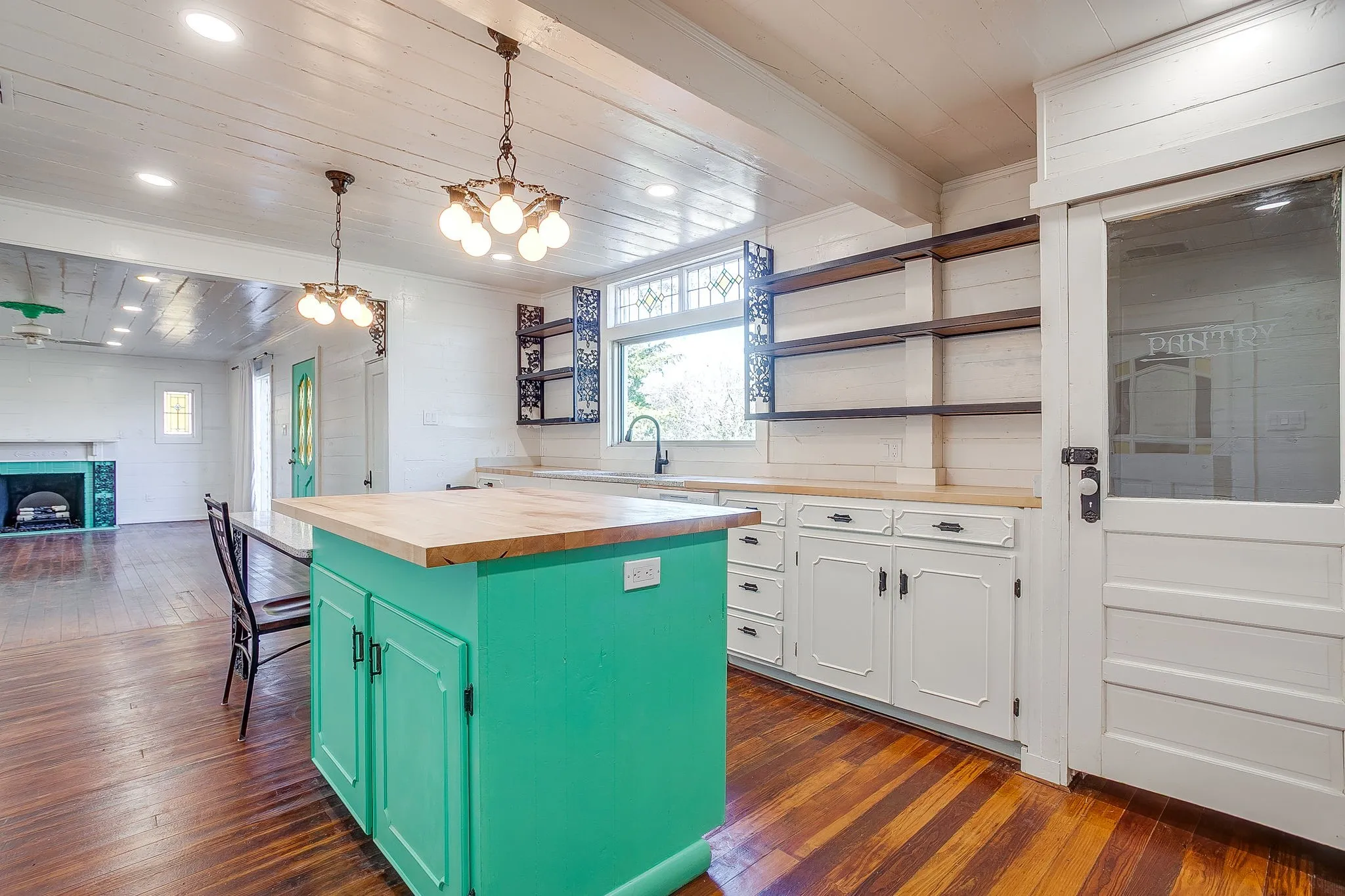 Kitchen with wooden counters, green cabinets, wooden ceiling, open shelves, and a kitchen island