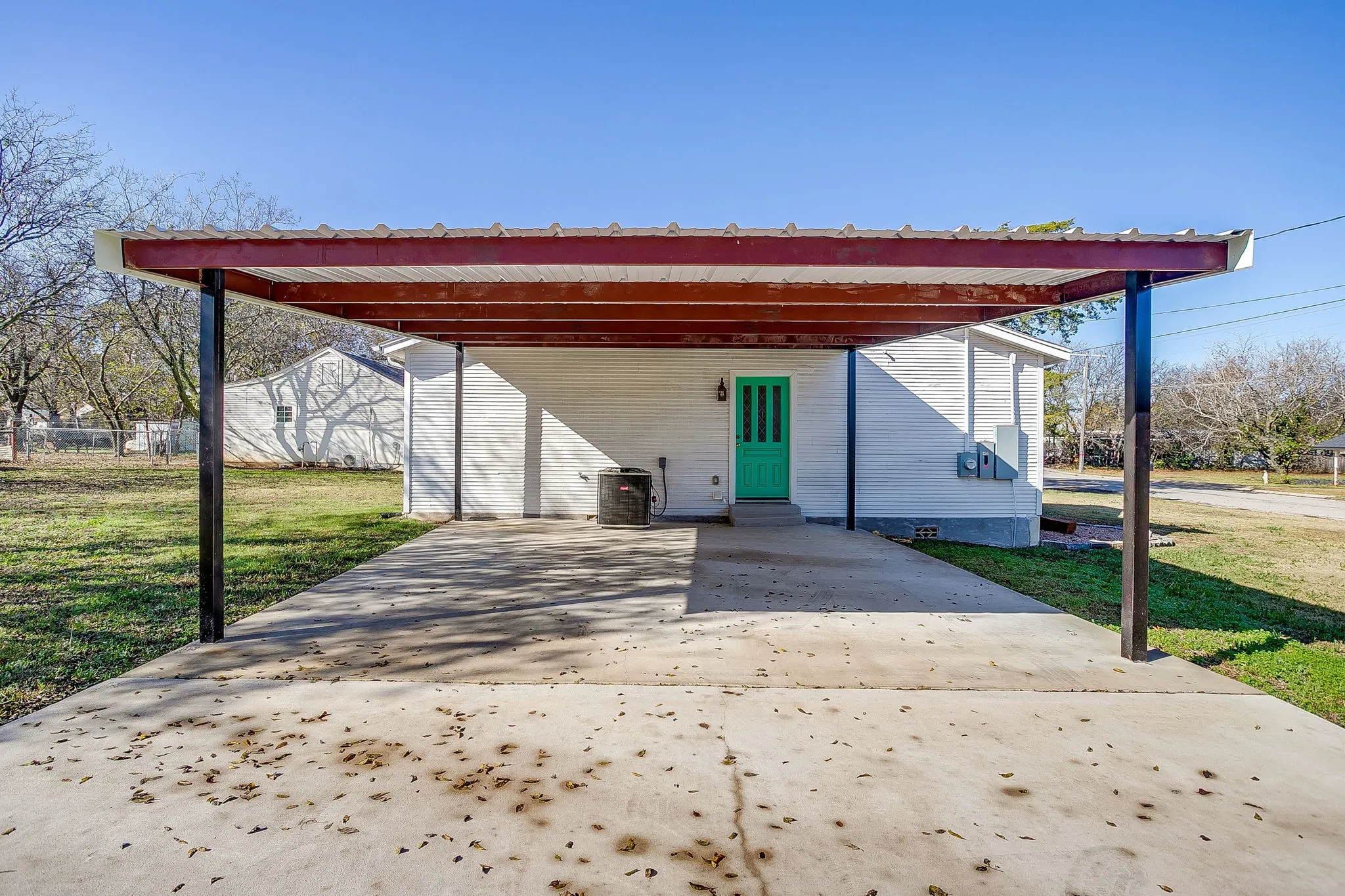 View of front facade featuring a front yard, an attached carport, and driveway
