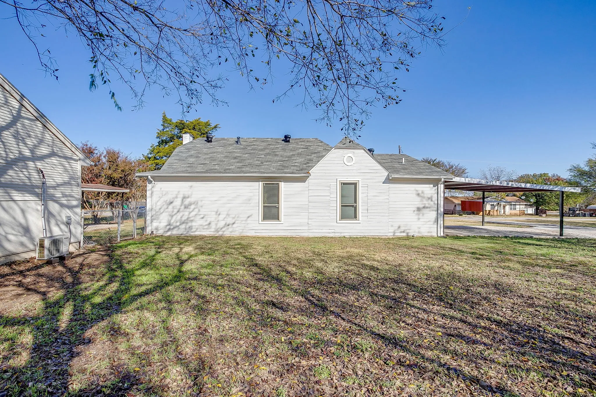 Back of house featuring a shingled roof and a carport