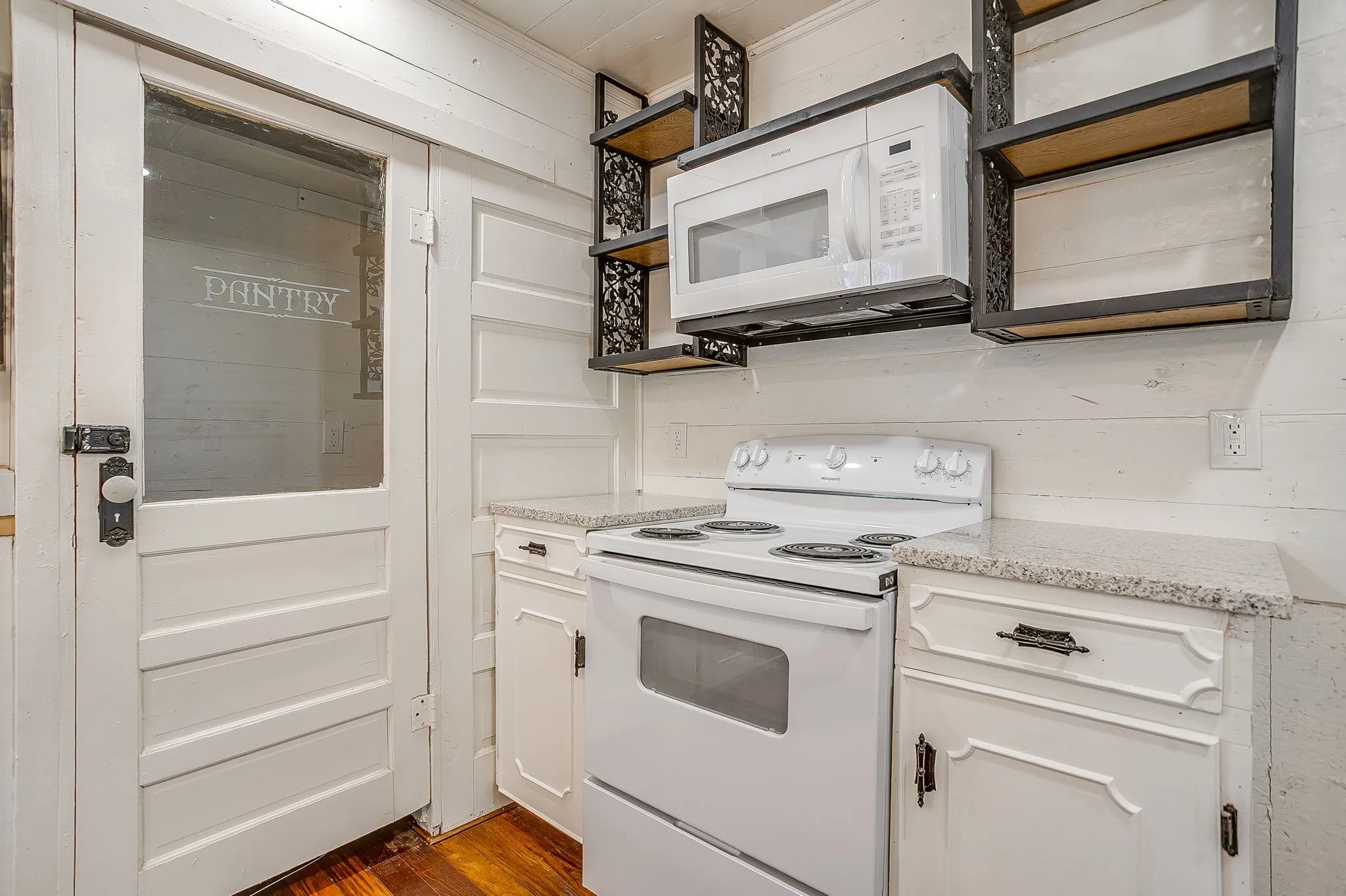 Kitchen featuring white appliances, open shelves, white cabinets, and light stone counters